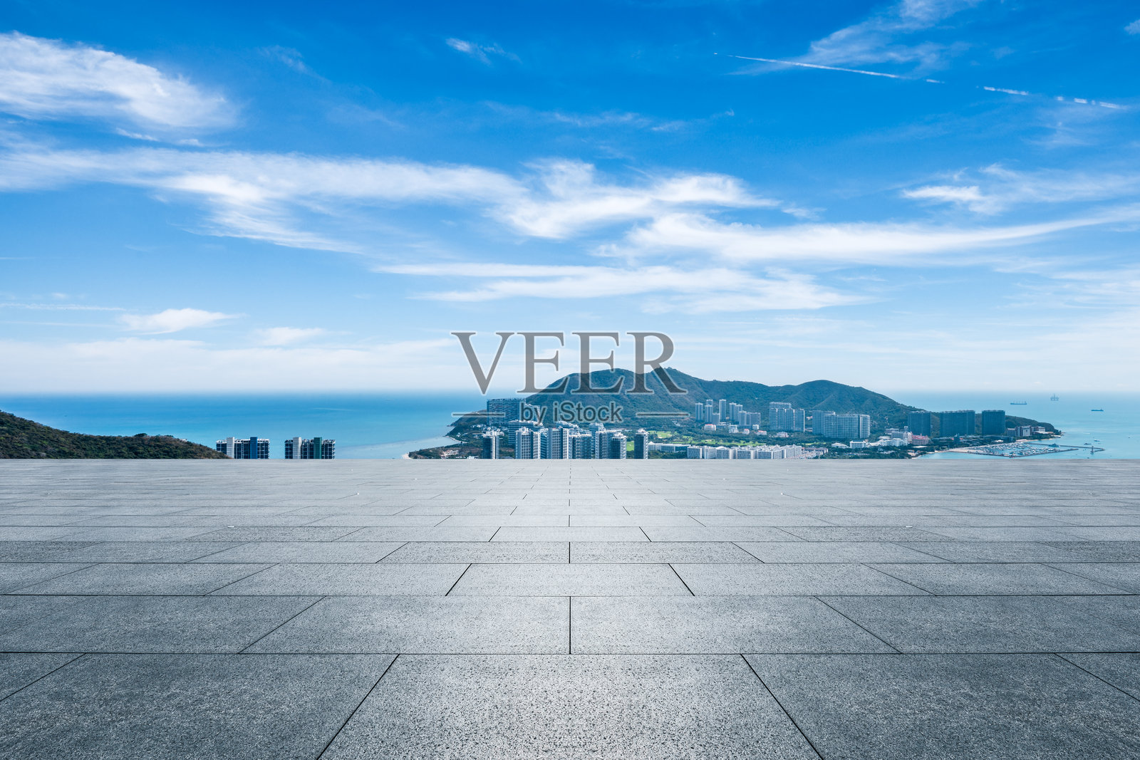 空旷的方形地面平台和海边城市建筑，蓝天之下的海洋照片摄影图片