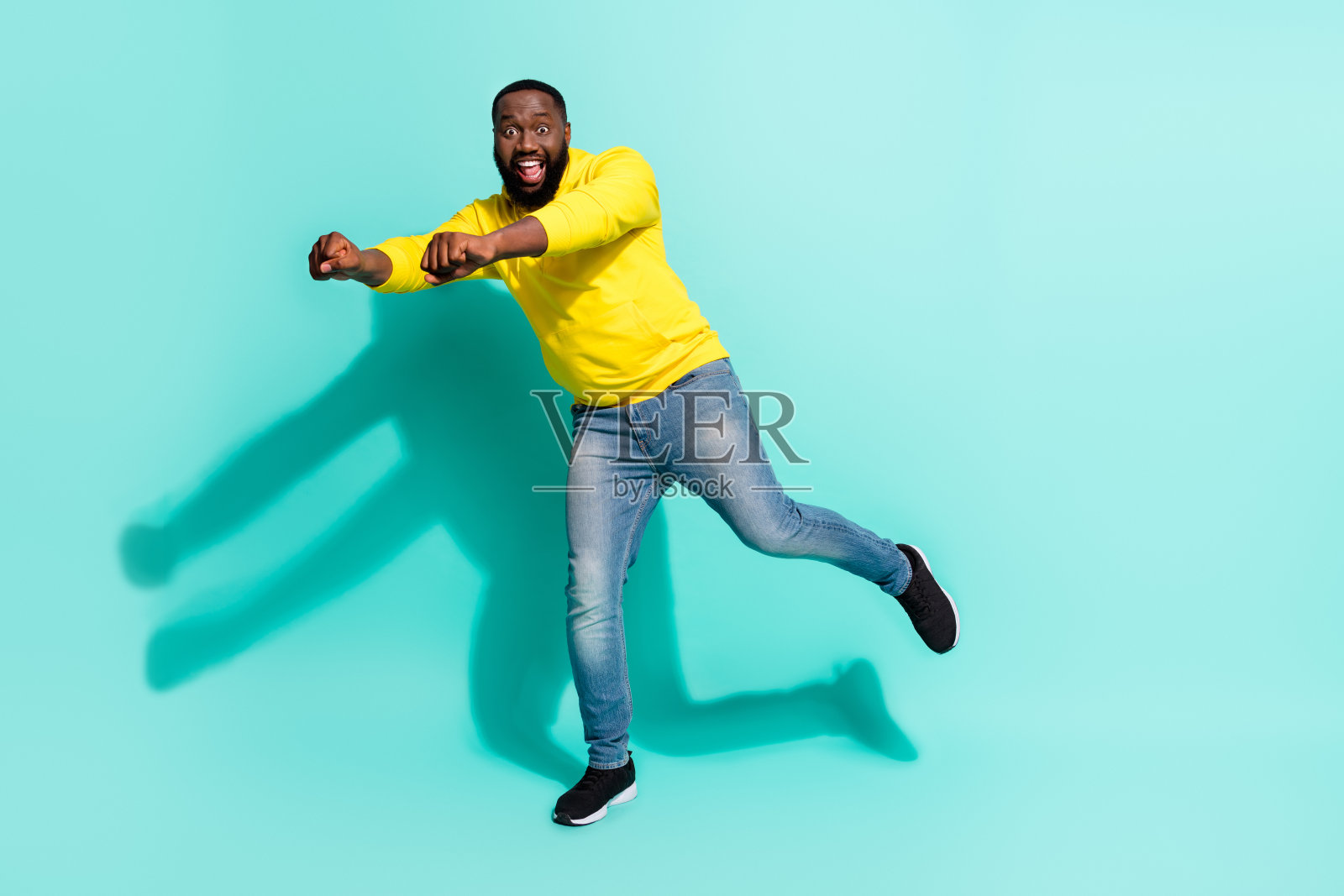 全身照，轻松自在的酷男孩在舞池上，骑着摩托车，想象着骑行者，背景为青色。照片摄影图片