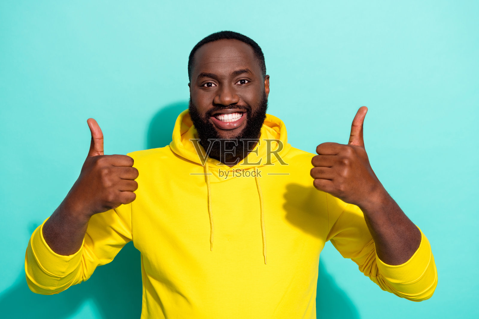 积极的男士竖起大拇指，暗示折扣促销，背景为青色。照片摄影图片