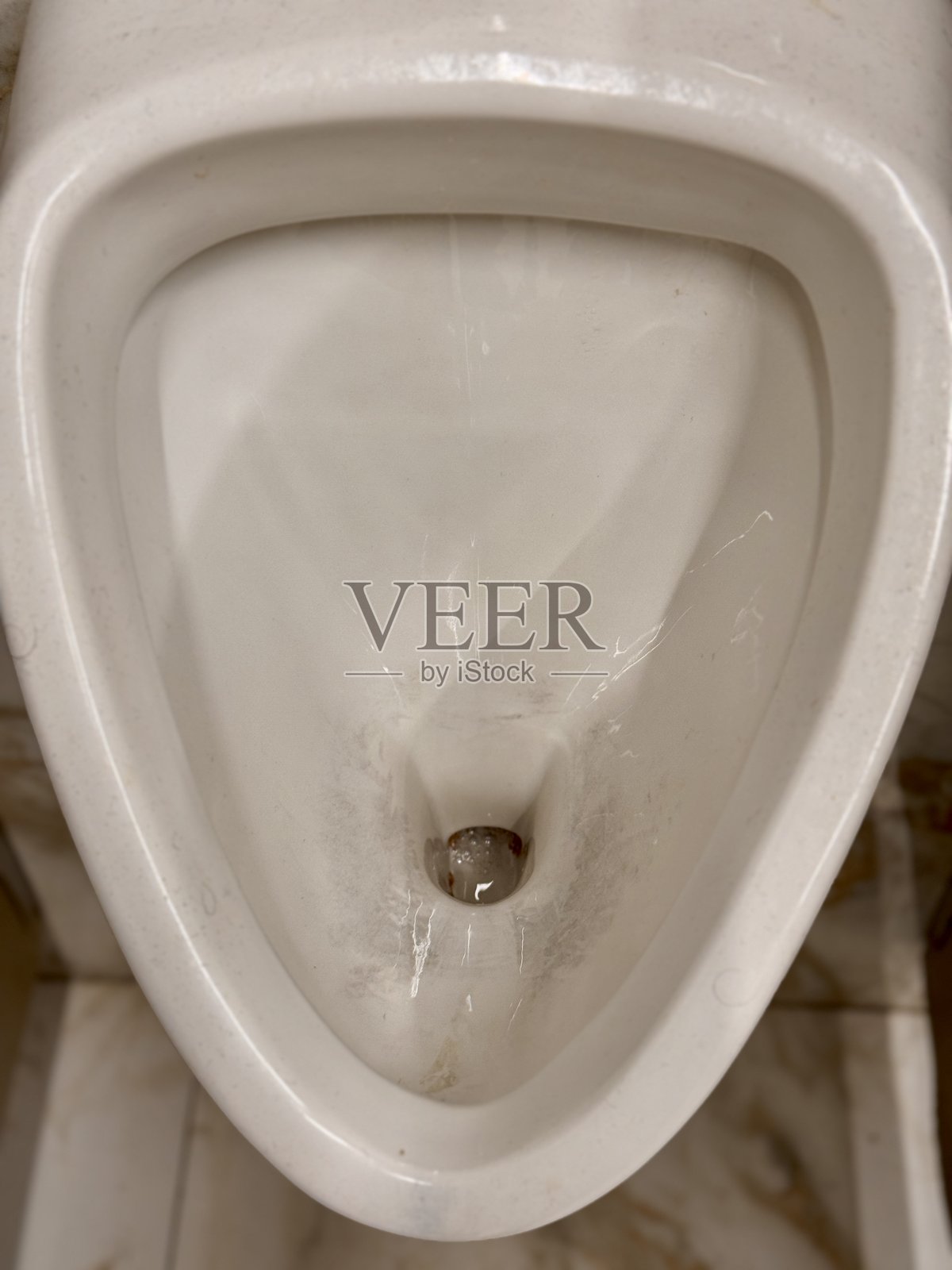 一个未维护的马桶出现在一个护理不善的公共卫生间环境中。一个肮脏、污渍斑斑的马桶展示了公共卫生间保持清洁的迫切需求。照片摄影图片