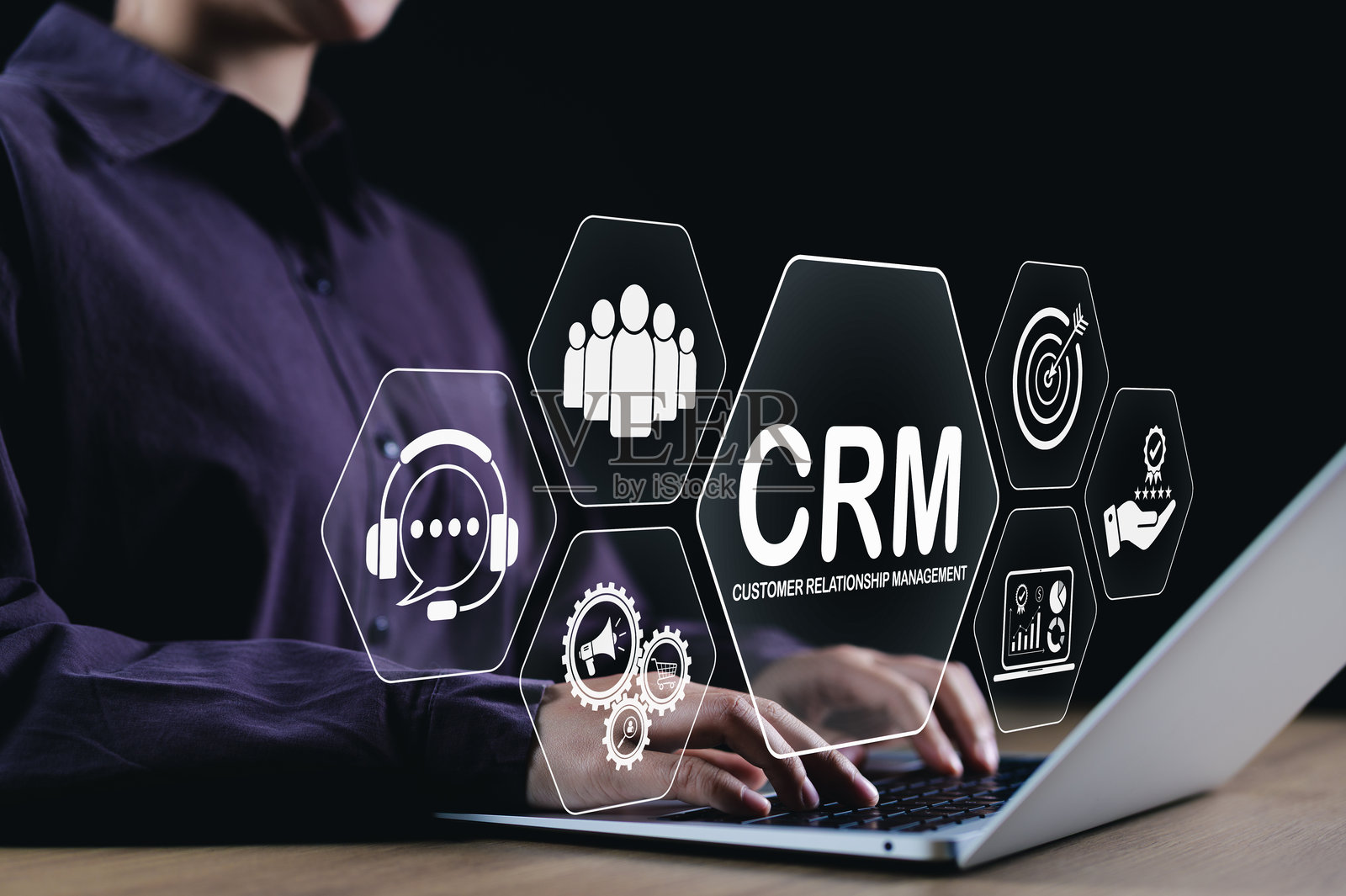 客户关系管理（CRM）概念。一位商务专业人士正在使用笔记本电脑，屏幕上显示着CRM图标，代表客户服务、分析、互动和关系管理工具。照片摄影图片