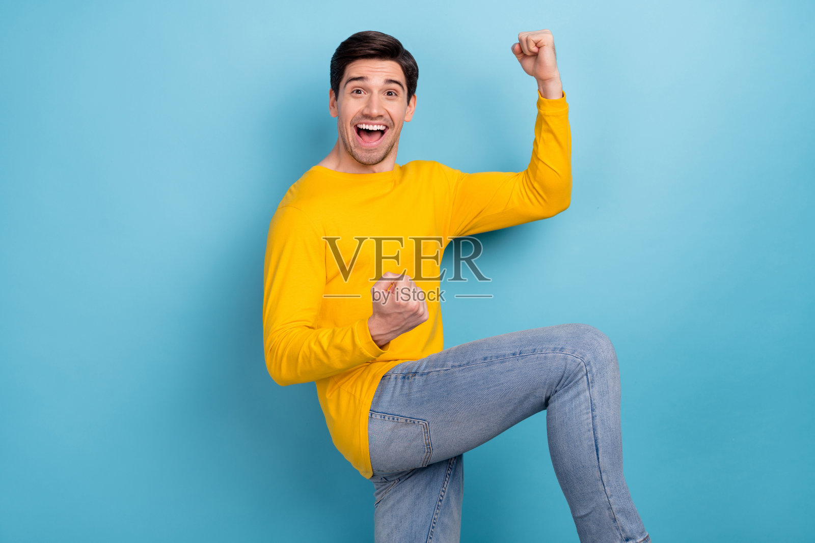 疯狂兴奋的男子在蓝色背景下举起双臂庆祝获胜照片摄影图片