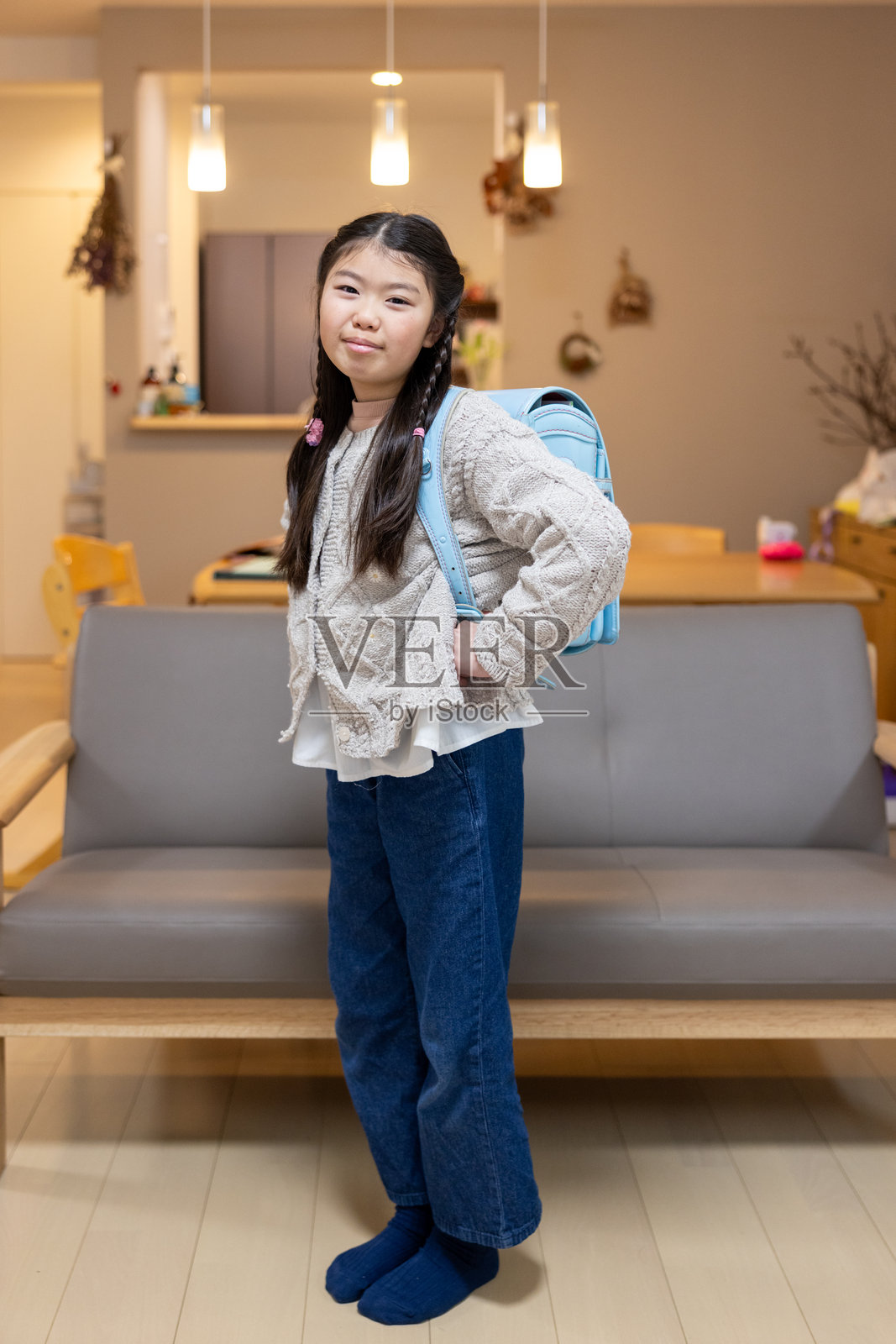 日本小学女生在客厅里背着“ランドセル”的全身肖像照片摄影图片