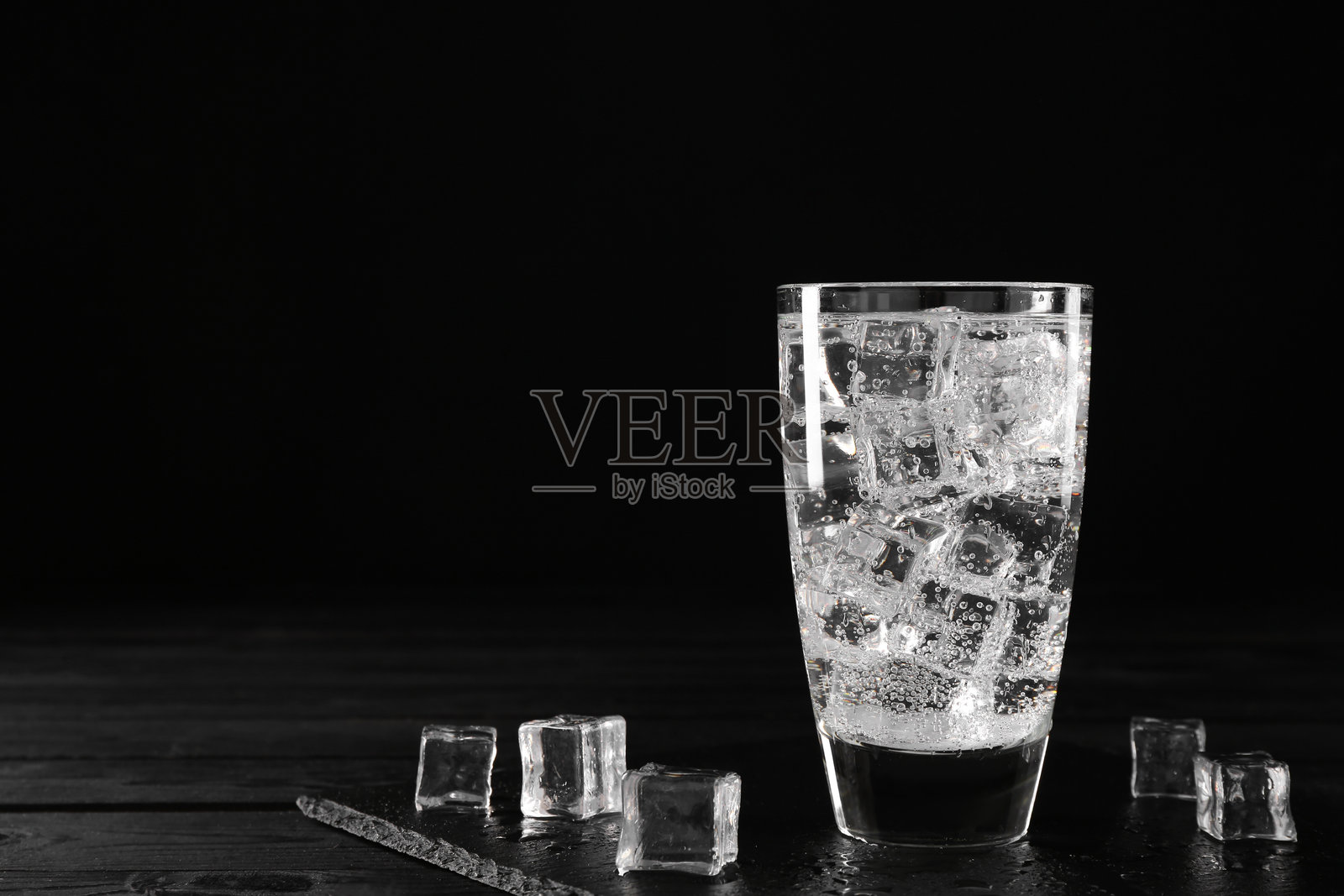 黑色木桌上的冰块玻璃杯中清爽的苏打水，留有文字空间照片摄影图片