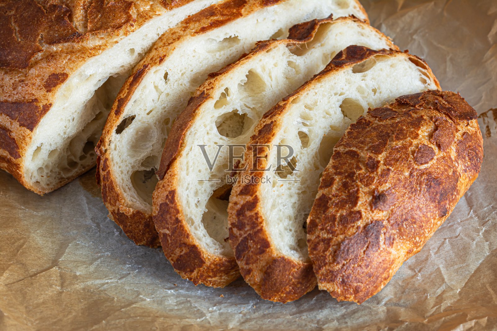 新鲜酥脆的老虎面包（荷兰面包），外皮美味，口感如家常自制，背景为质朴的木材。面包表面有裂纹。照片摄影图片