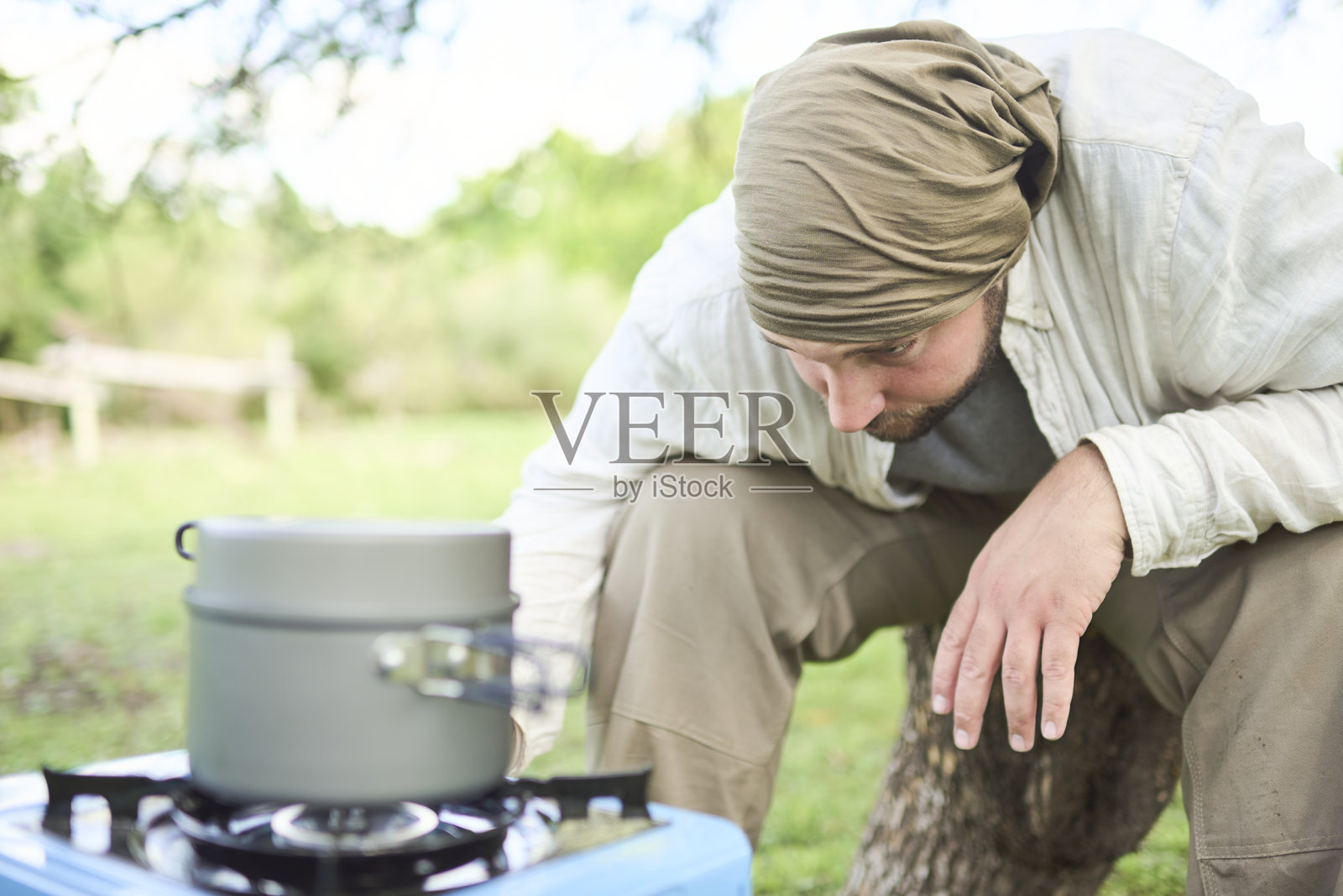 年轻男性旅行者在露营时使用便携式炉灶户外烹饪。照片摄影图片