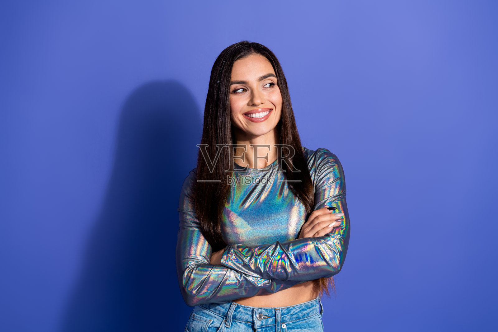 一位迷人的年轻女性，长着棕色的头发，穿着休闲的全息上衣，背景是充满活力的紫色，她自信地微笑着。照片摄影图片