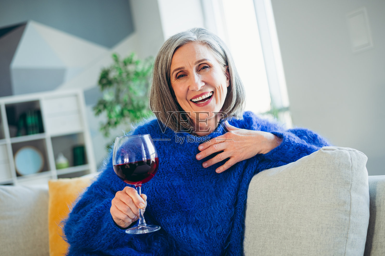 迷人的成熟的女性在室内享受悠闲时光，手握饮品，穿着温暖的毛衣，感受舒适。照片摄影图片