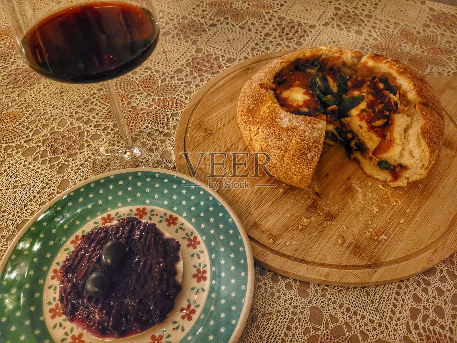 意大利面包夹着菠菜、融化的米纳斯奶酪和番茄酱，部分切片并摆放在木板上，准备上桌的晚餐照片摄影图片