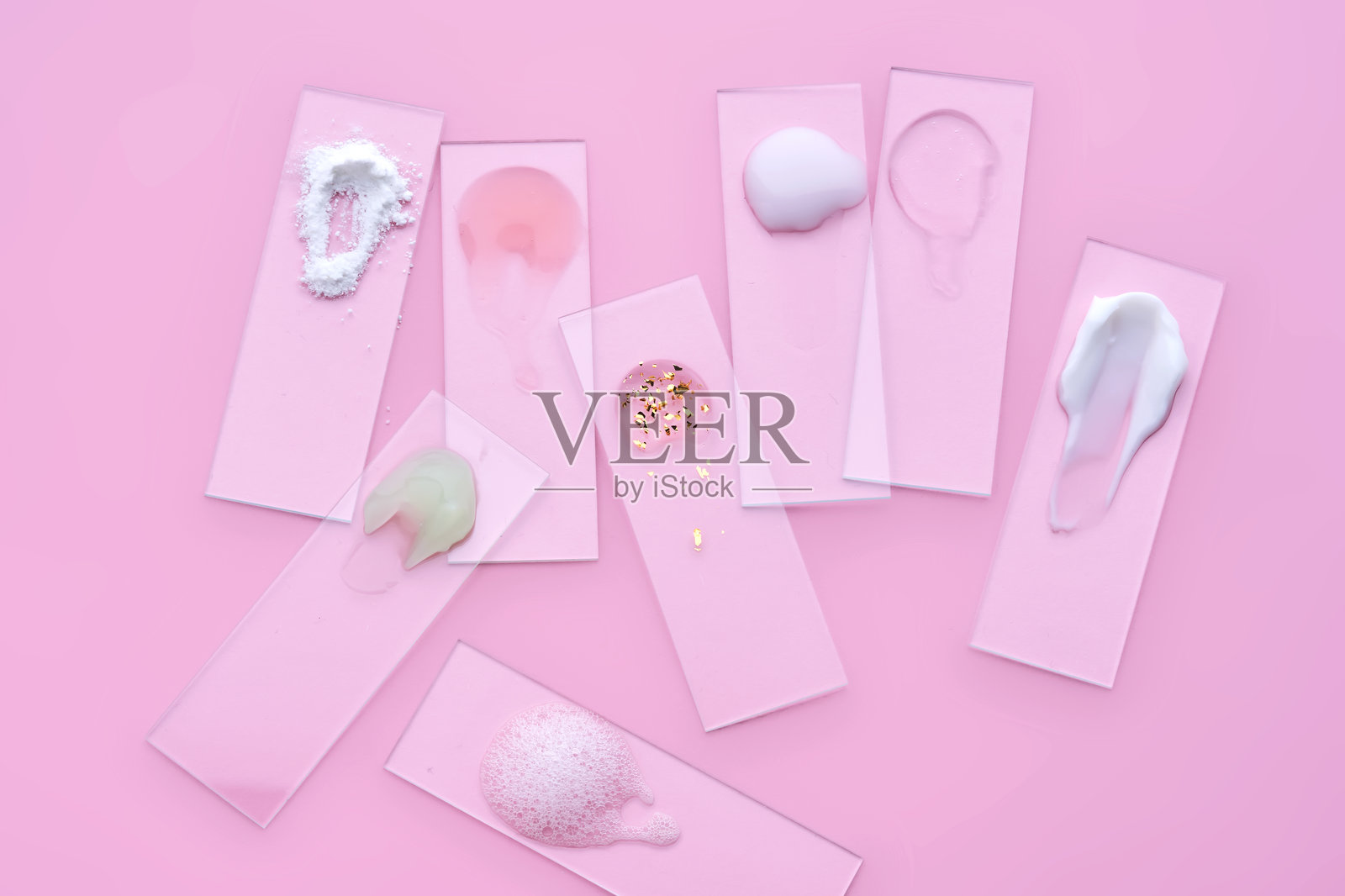 粉色背景上的各种化妆品：面霜和精华液的幻灯片。照片摄影图片