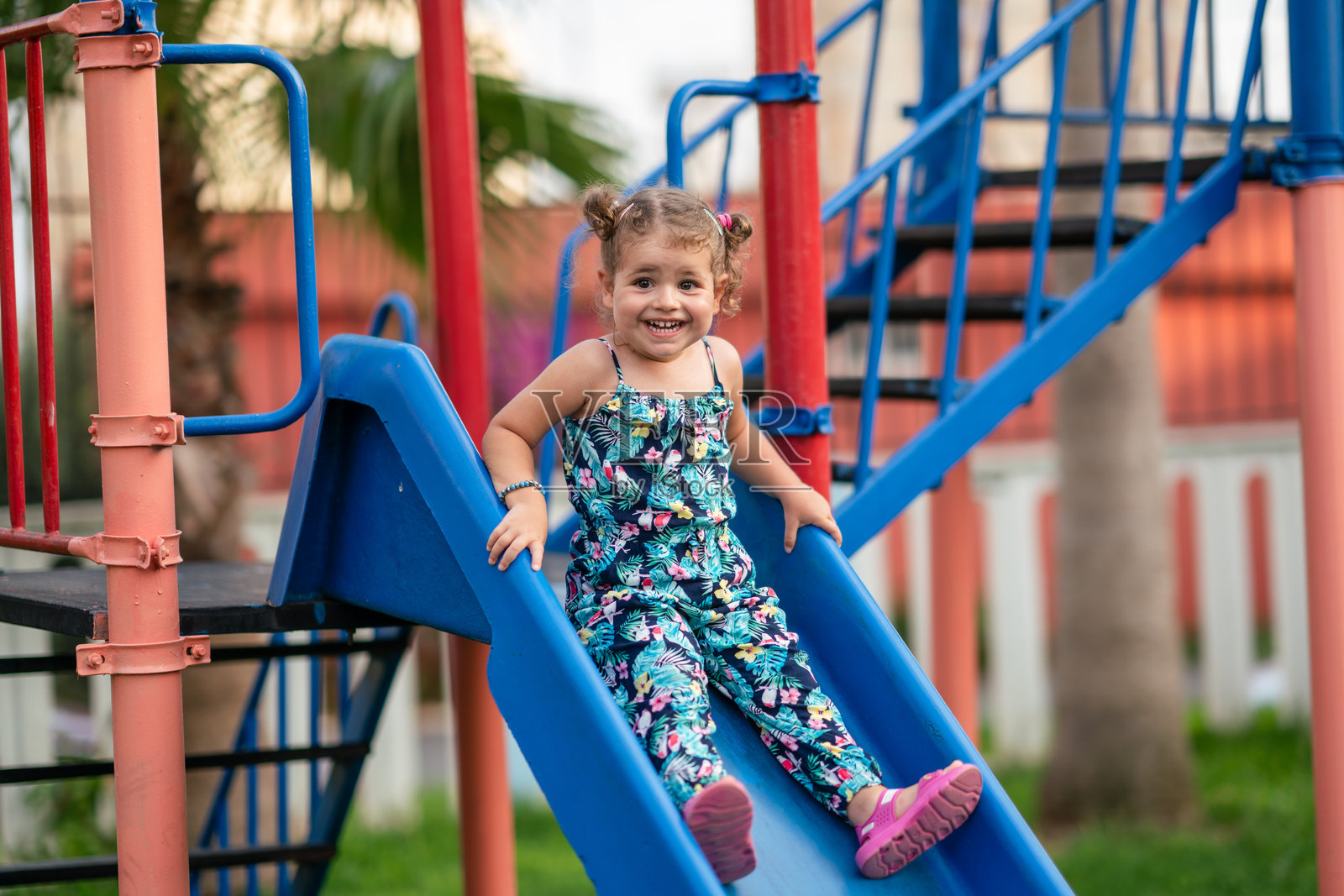 小女孩正在准备在游乐场的滑梯上滑下去。照片摄影图片