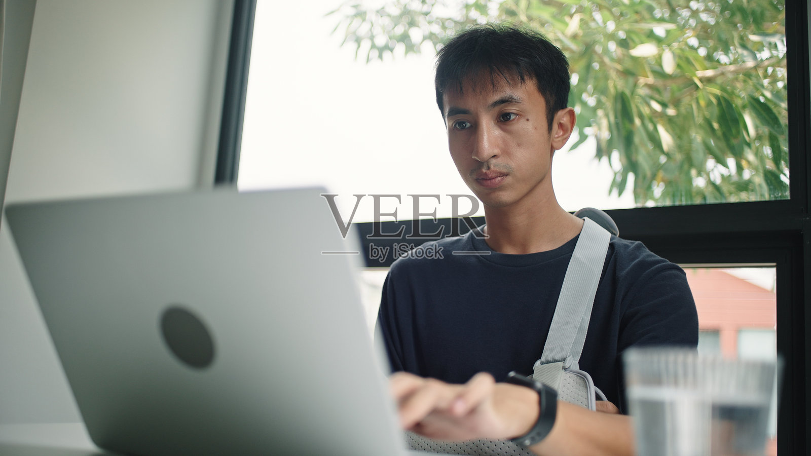 受伤男子使用笔记本电脑。照片摄影图片