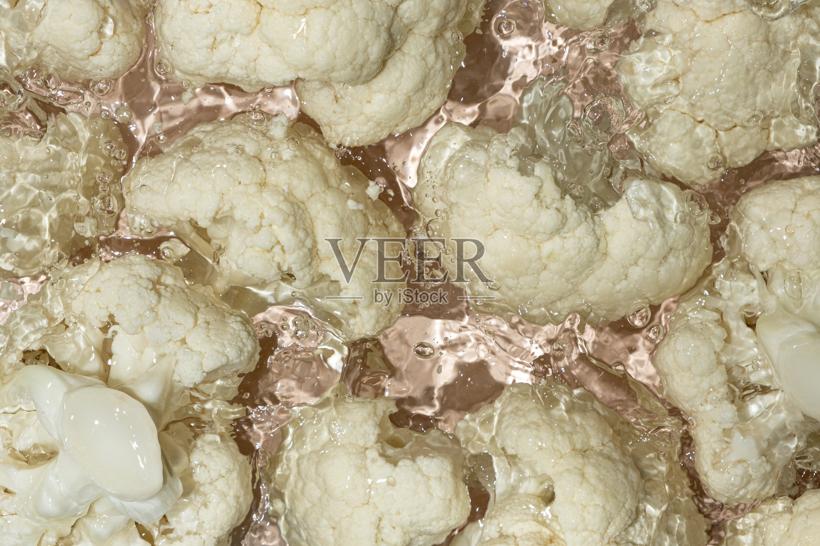 新鲜的花椰菜掉入水中，溅起水花。照片摄影图片