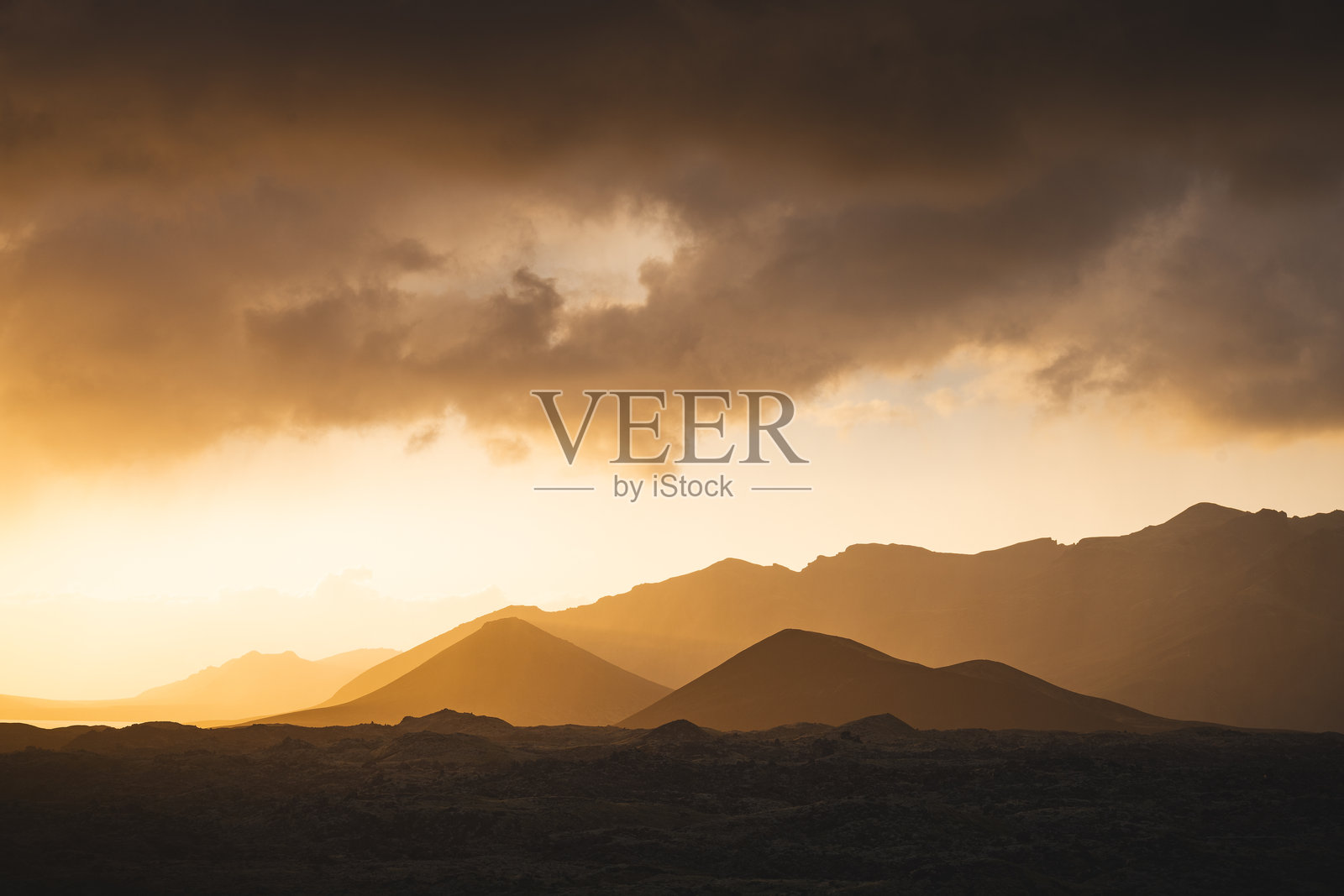 冰岛Stykkisholmsbar区Selvallavatn湖附近的Berserkjahraun熔岩场上空的金色日落。一个沐浴在温暖光线中的超现实火山景观。照片摄影图片