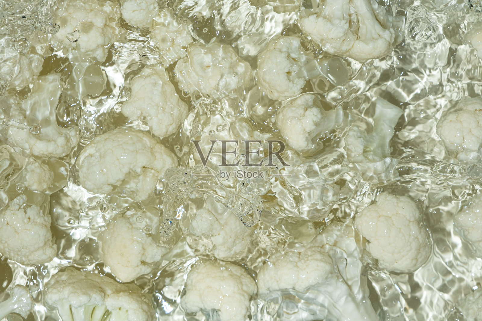 新鲜的花椰菜掉入水中，溅起水花。照片摄影图片