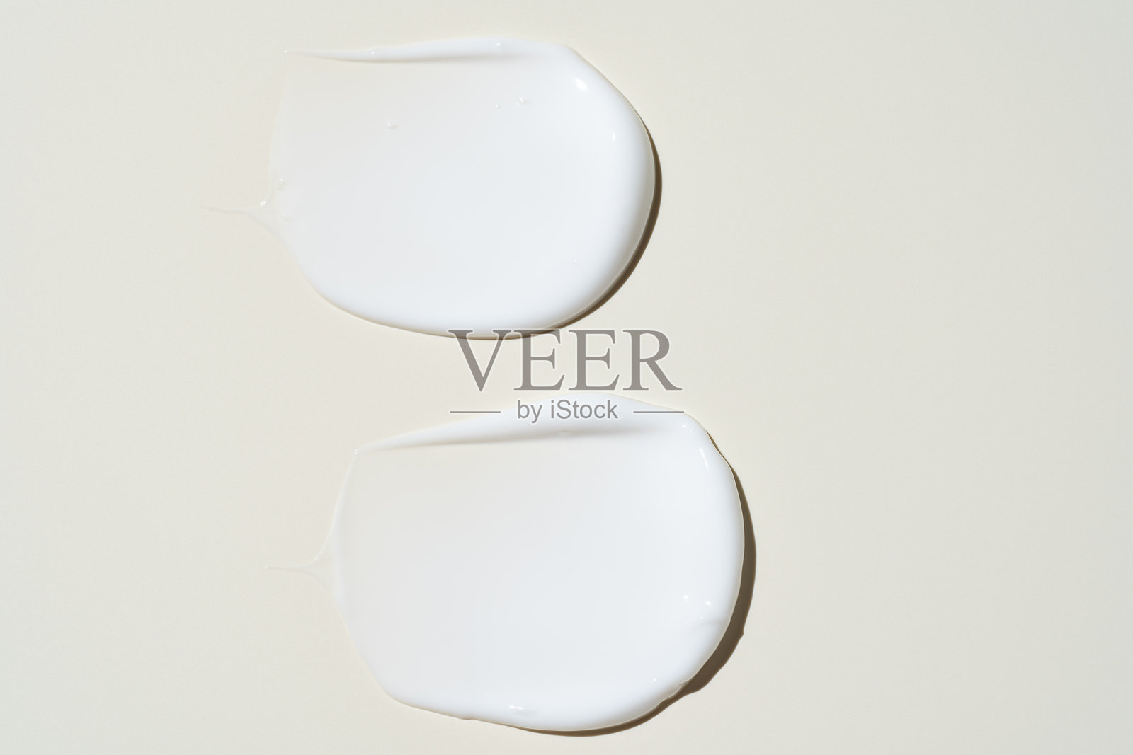 米色背景上的白色奶油质地。保湿霜的涂抹特写。乳液样本。美容护肤产品的涂抹痕迹。米色背景上的防晒霜样本。照片摄影图片