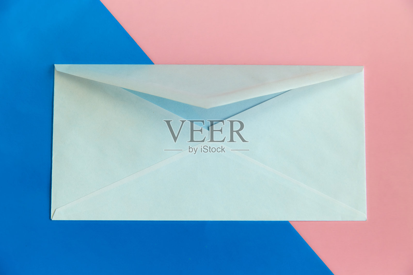 一封白色信封放在蓝粉色背景上，亲密的信件，在线约会，背景。照片摄影图片