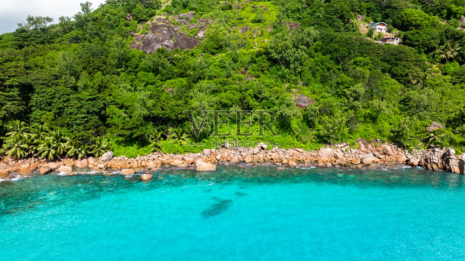 绿松石色的水域与岩石海岸和绿植。普拉斯林岛，塞舌尔。照片摄影图片