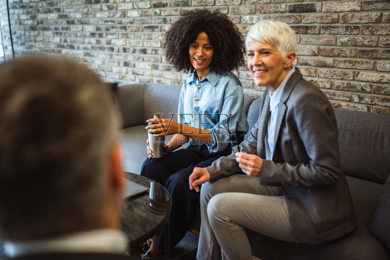 两位不同背景的同事在咖啡休息时间与男性同事聊天照片摄影图片