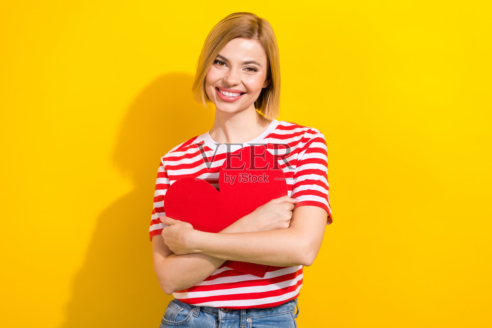 美丽女孩穿着时尚夏装，手持大红明信片礼物，背景为黄色。照片摄影图片