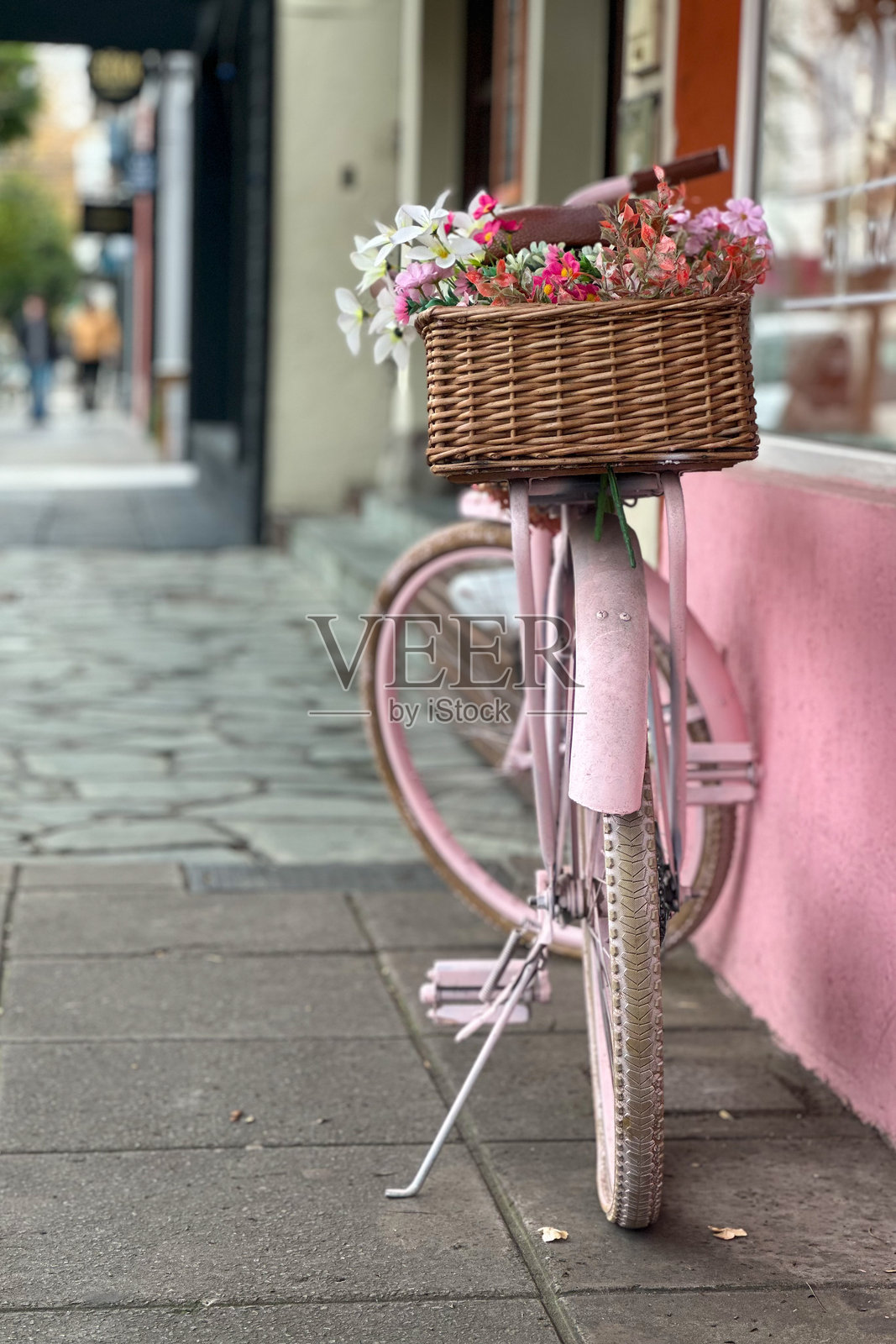 环保街头美学 创意再利用 – 花朵装饰的粉色自行车在房屋入口处照片摄影图片