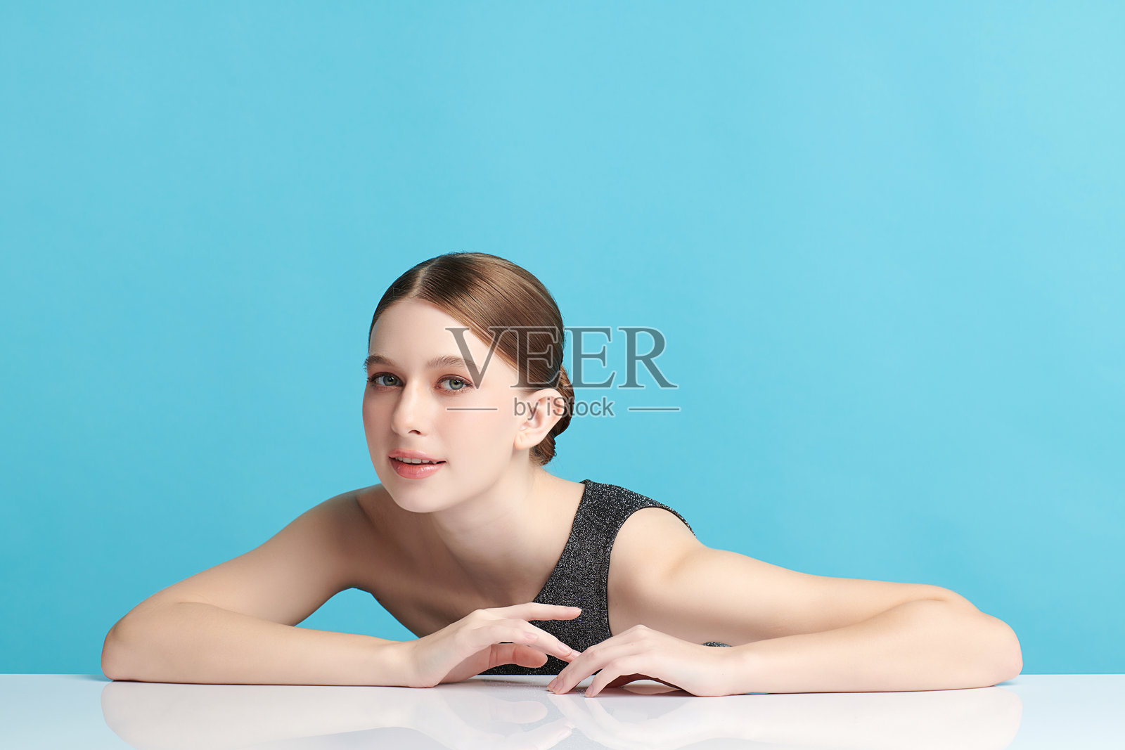 一位年轻美丽的女性，皮肤洁净清新，背景为蓝色。护肤、面部护理、美容学、美丽和水疗。女性的优雅肖像。照片摄影图片