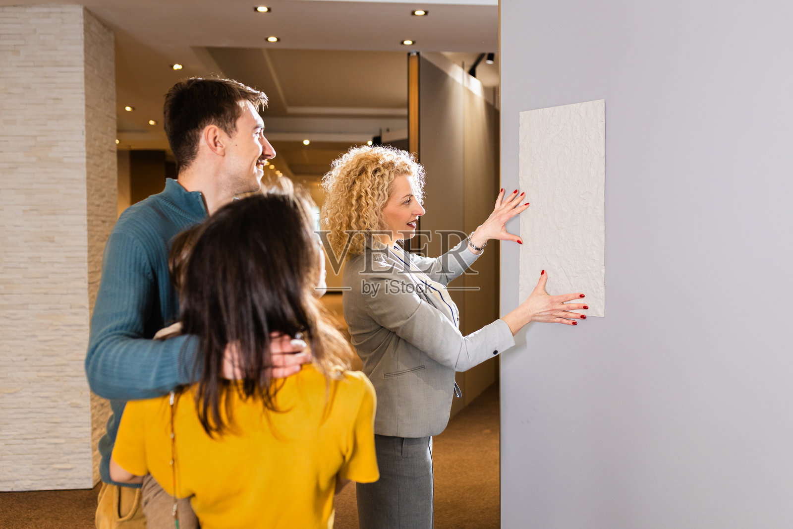 女销售员向一对带着孩子的年轻夫妇展示家居室内装饰面板。照片摄影图片