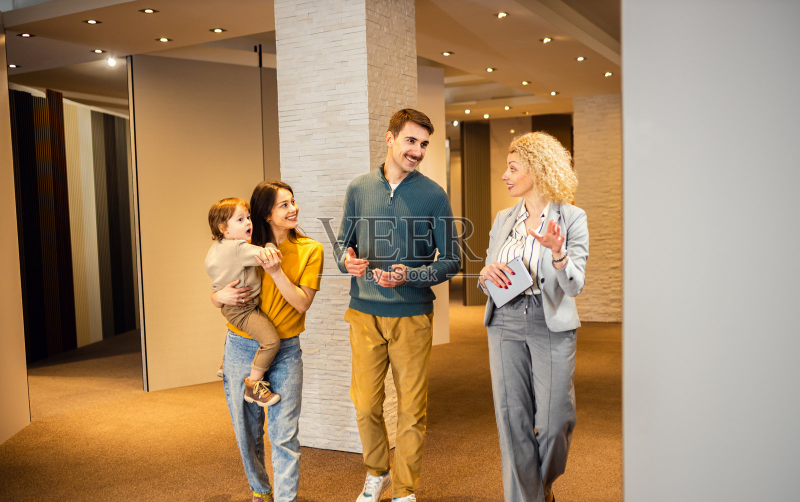 女销售员向一对带着孩子的年轻夫妇展示家居室内装饰面板。照片摄影图片