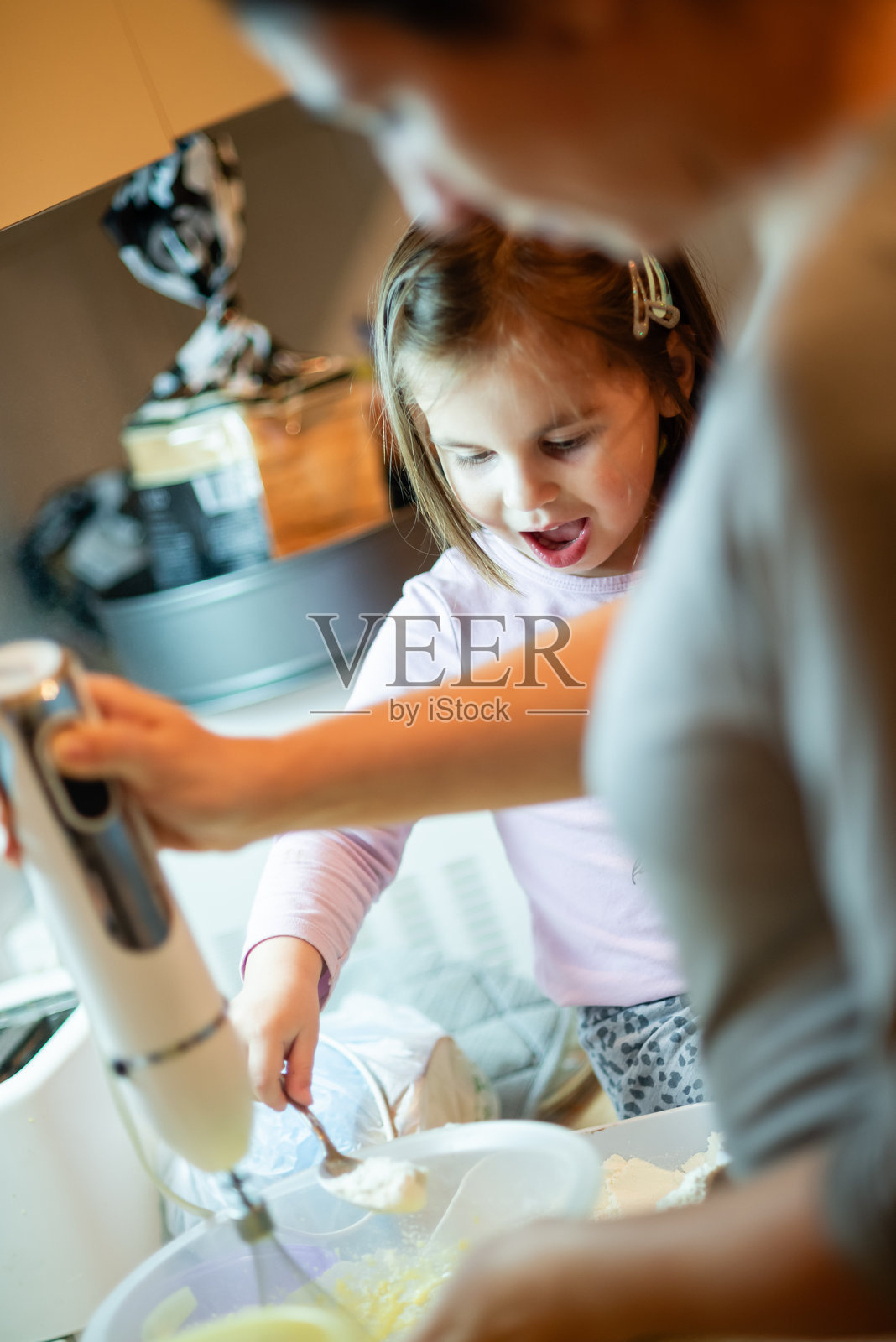 小女孩在厨房里和妈妈一起用电动搅拌器添加面粉照片摄影图片