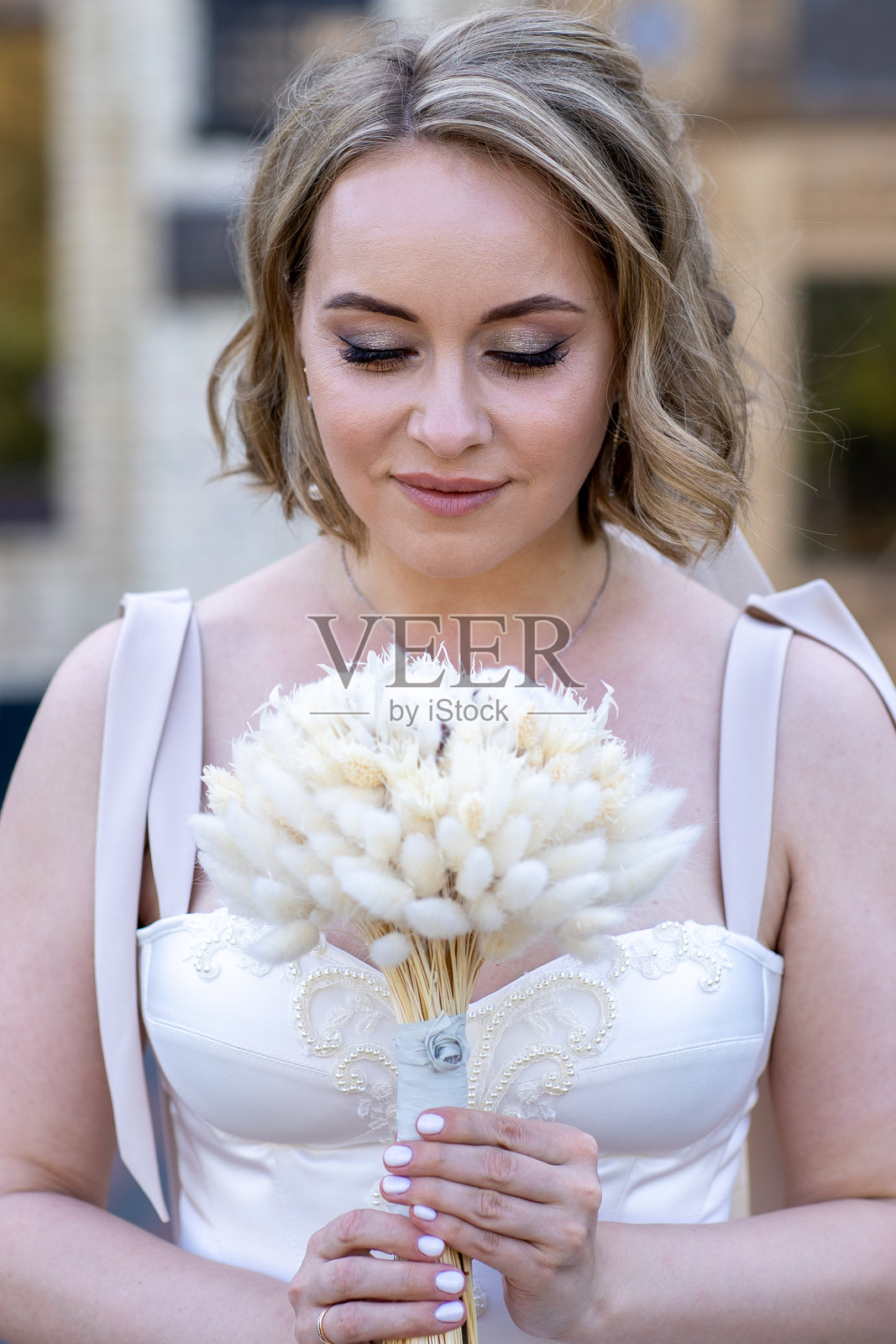 美丽年轻新娘的肖像，身穿白色婚纱，手捧花束。婚礼当天。户外婚纱摄影。照片摄影图片