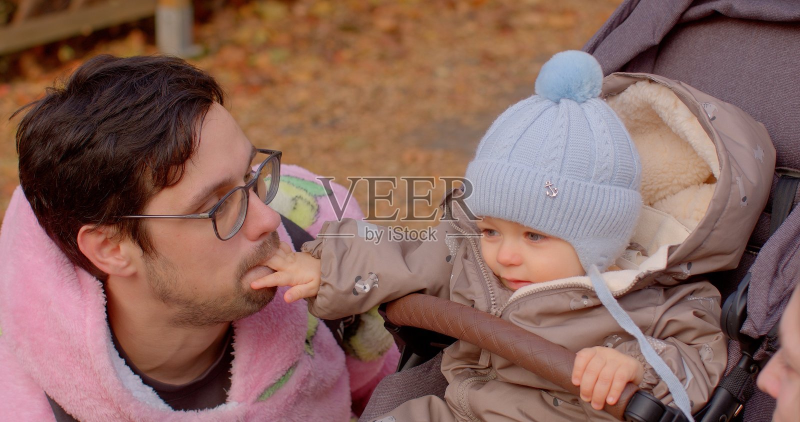 父亲和孩子在秋天的公园里享受推车散步。照片摄影图片