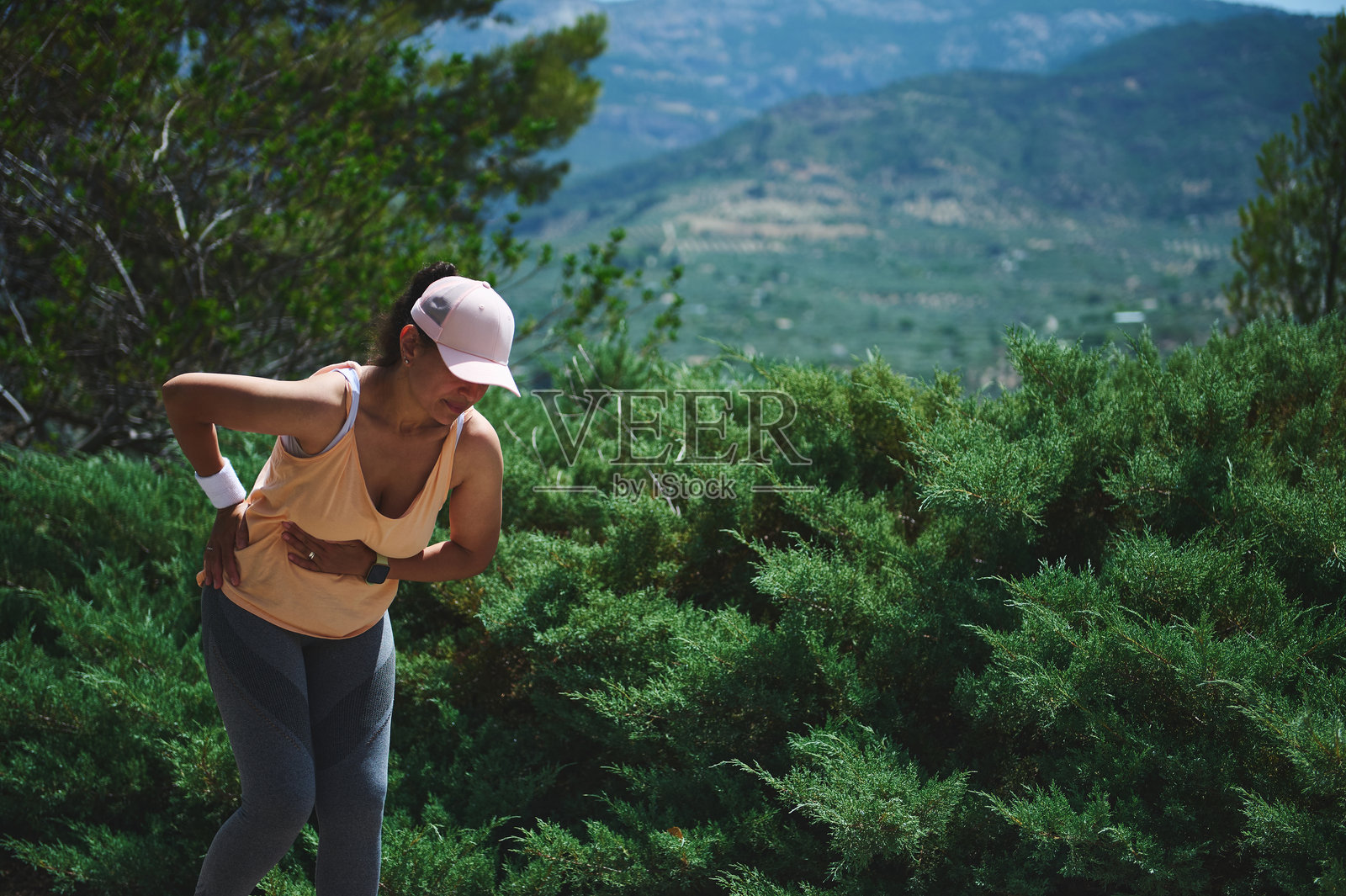 女性在大自然中户外锻炼时暂停，四周被绿色灌木和美丽的山脉环绕照片摄影图片