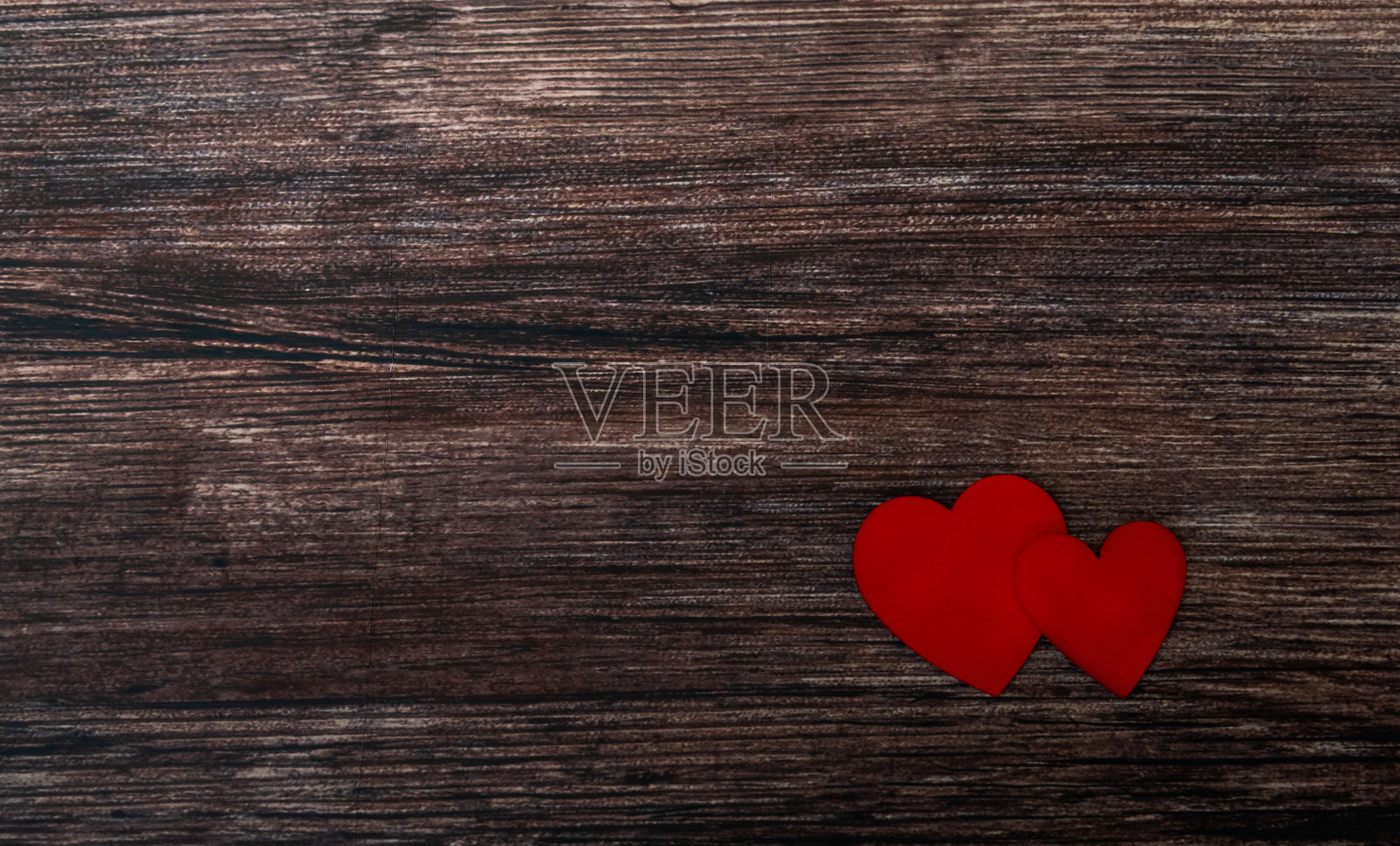 情人节背景，两个红色心形图案放在褐色风化的木桌上照片摄影图片