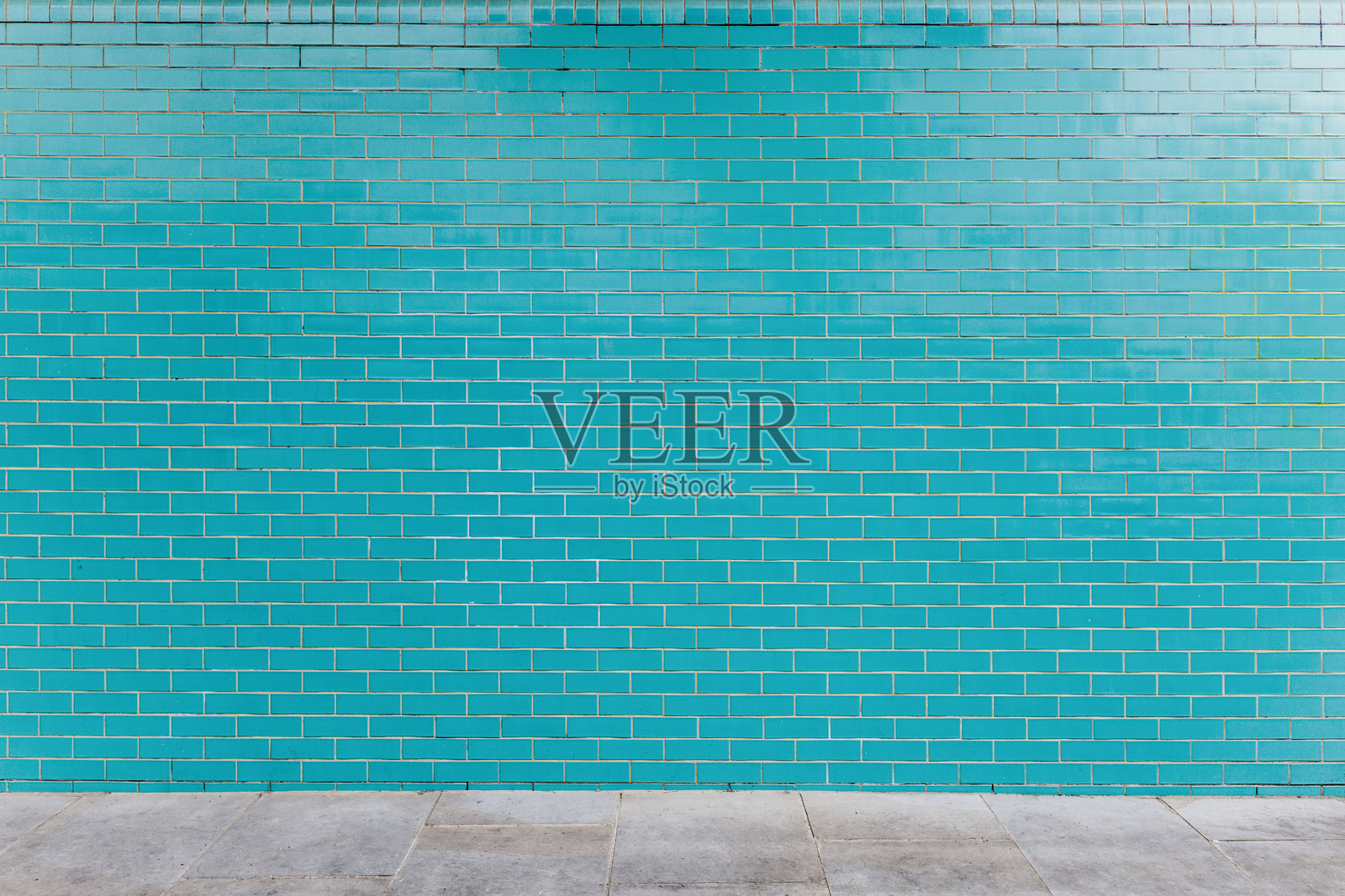 鲜艳的青绿色砖墙与混凝土人行道相接照片摄影图片