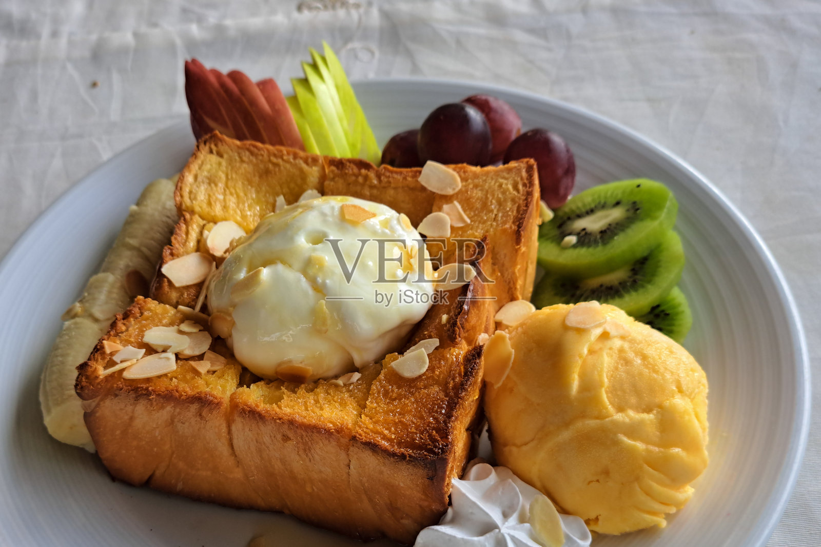 蜂蜜吐司上的冰淇淋。温暖的吐司上放着冰淇淋，美味的甜点。蜂蜜吐司和冰淇淋配混合水果。照片摄影图片