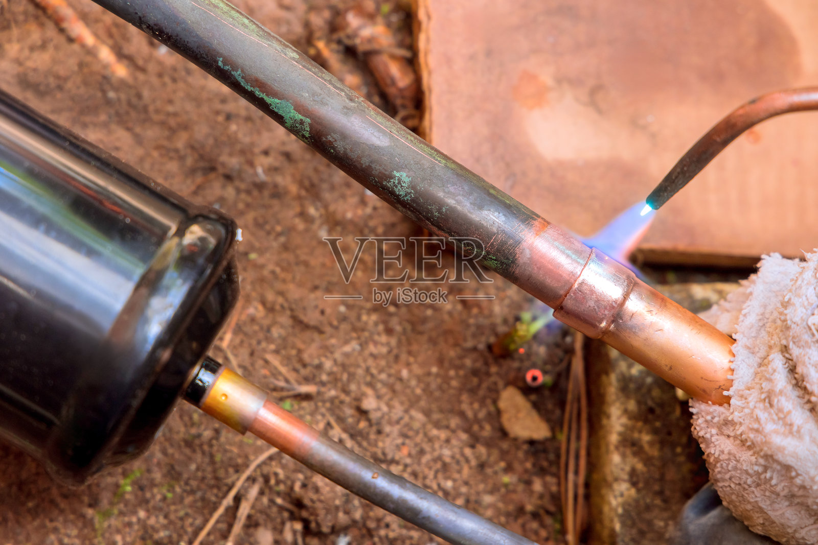 在车间环境中，使用火焰对铜管进行焊接，以进行暖通空调维护。照片摄影图片