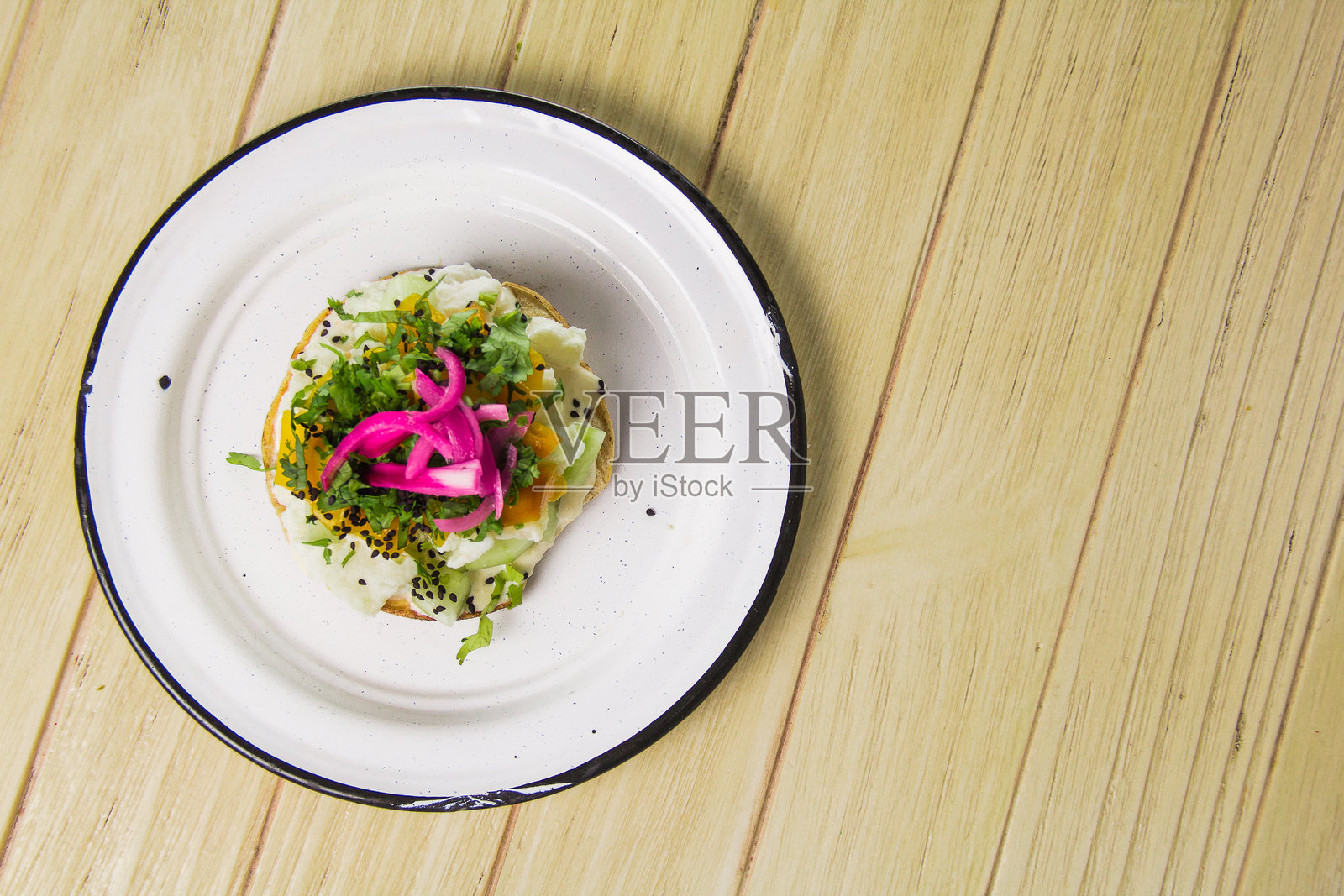 一份新鲜的海鲜玉米饼，摆放在单独的盘子上，配有色彩丰富的配料，如腌制洋葱、黄瓜和香草，强调健康饮食选择。照片摄影图片