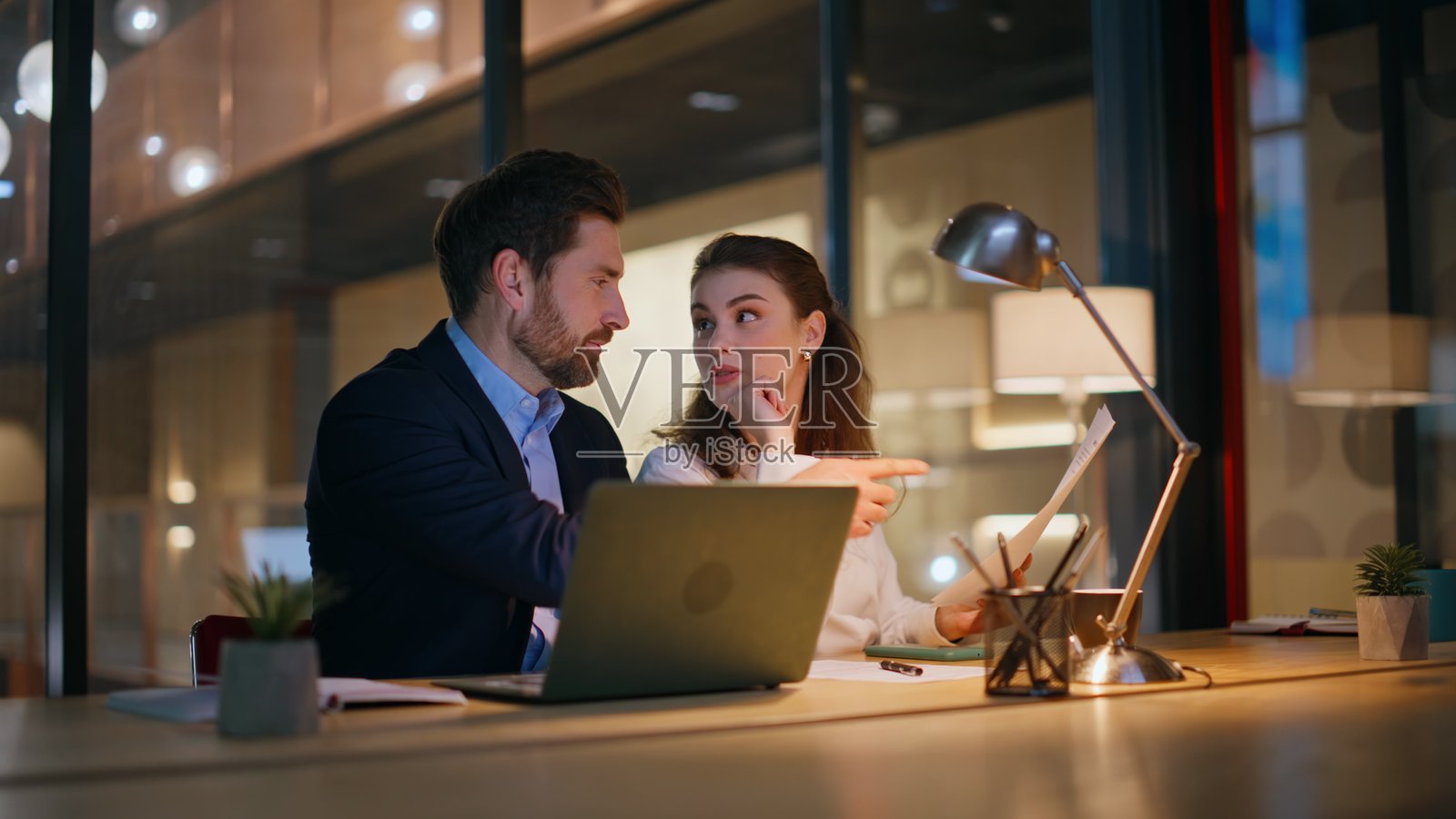 创意创业者在现代办公室讨论战略，夜晚时分。照片摄影图片