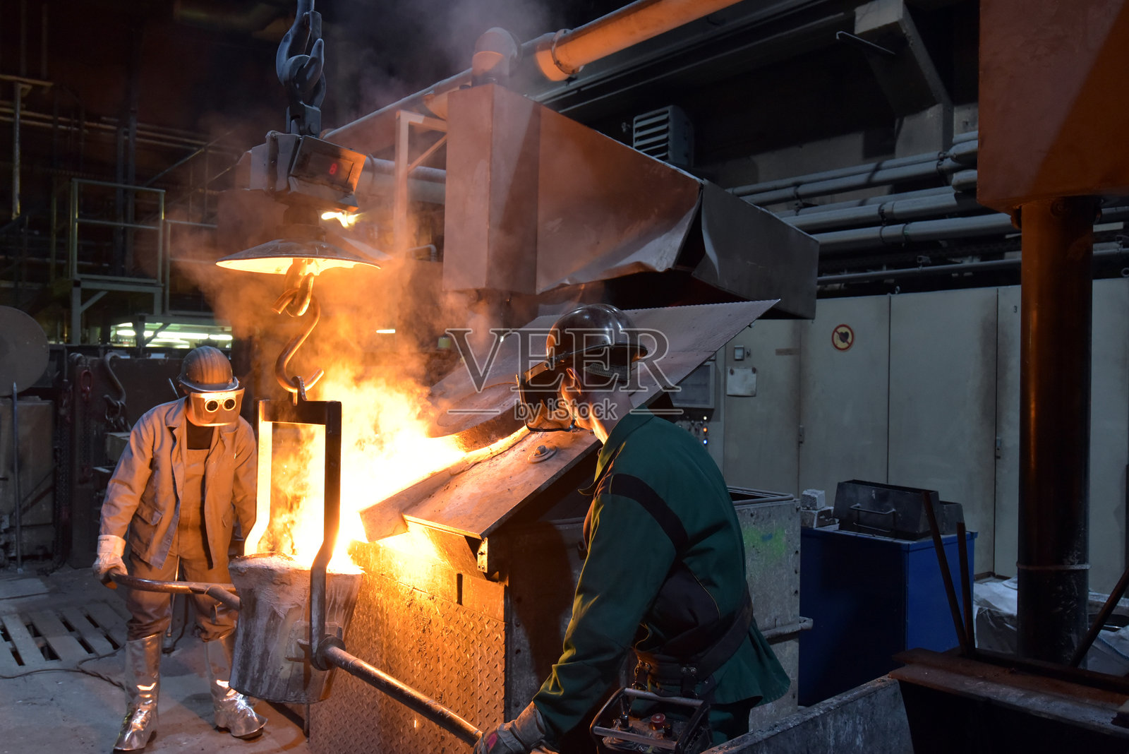 铸造厂的工人在铸造金属工件 - 工作安全与团队合作照片摄影图片