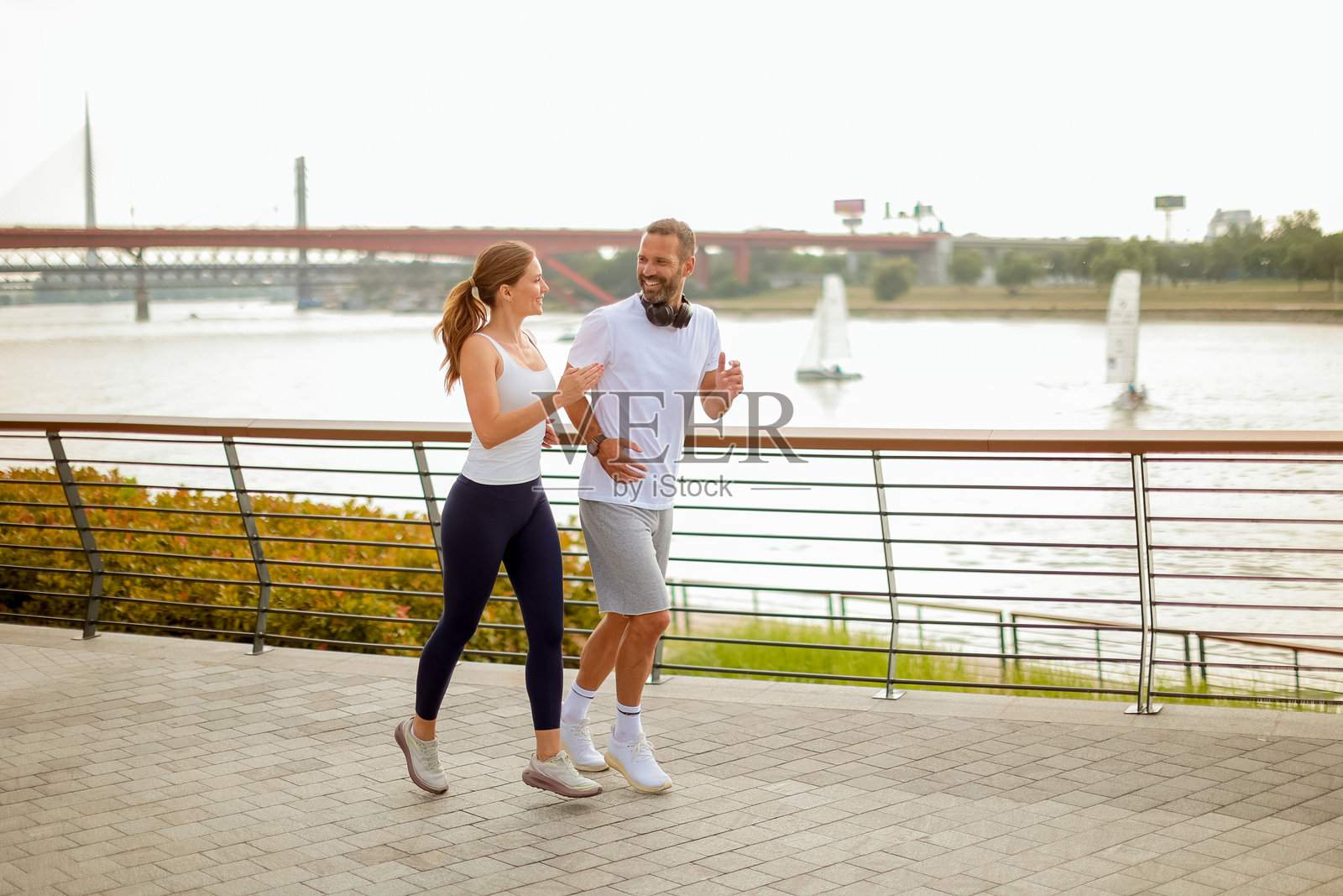 情侣在充满活力的城市环境中沿着河边小道晨跑照片摄影图片