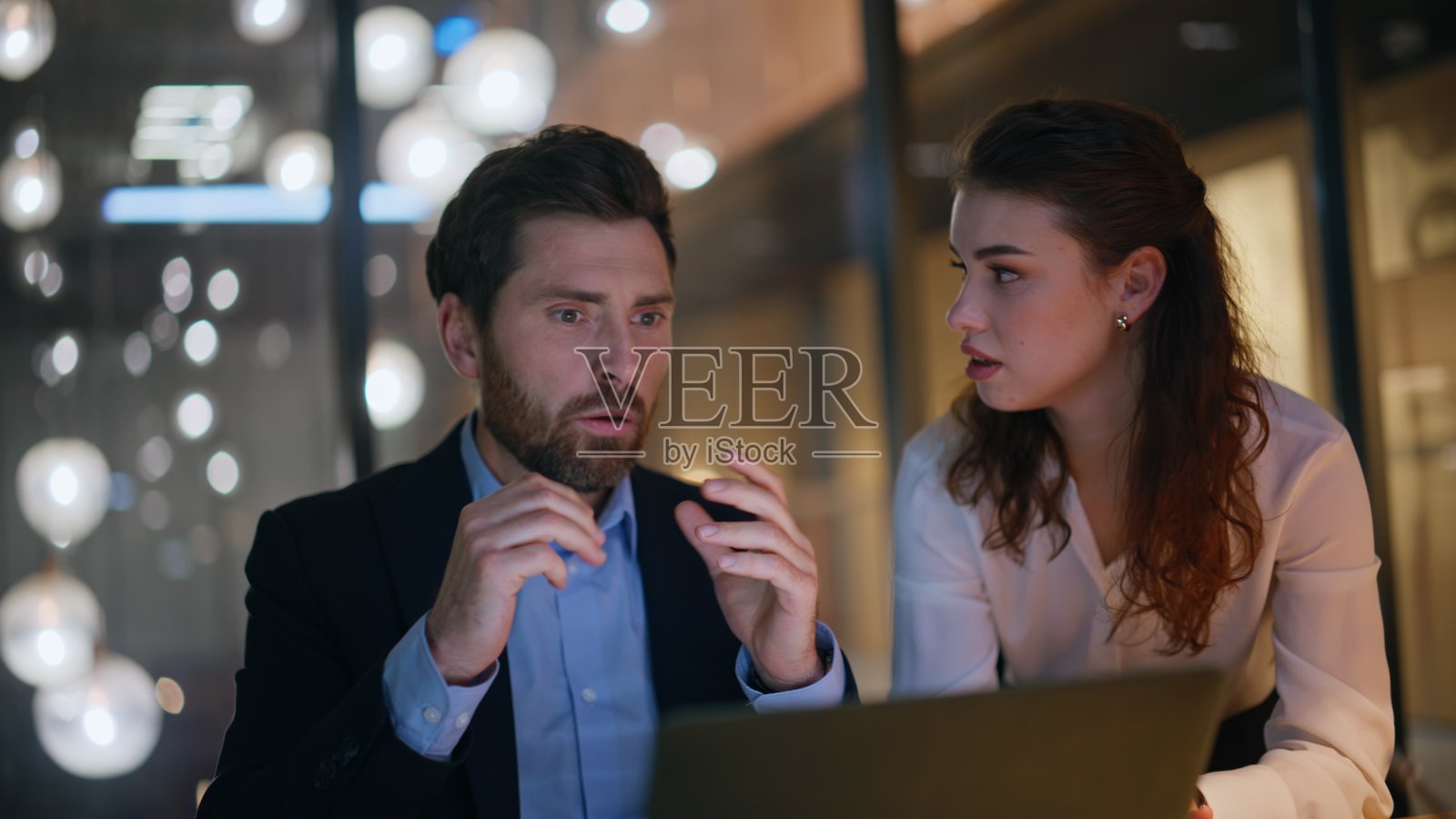 绝望的同事在夜间办公室里近距离观察电脑对失落的反应。照片摄影图片