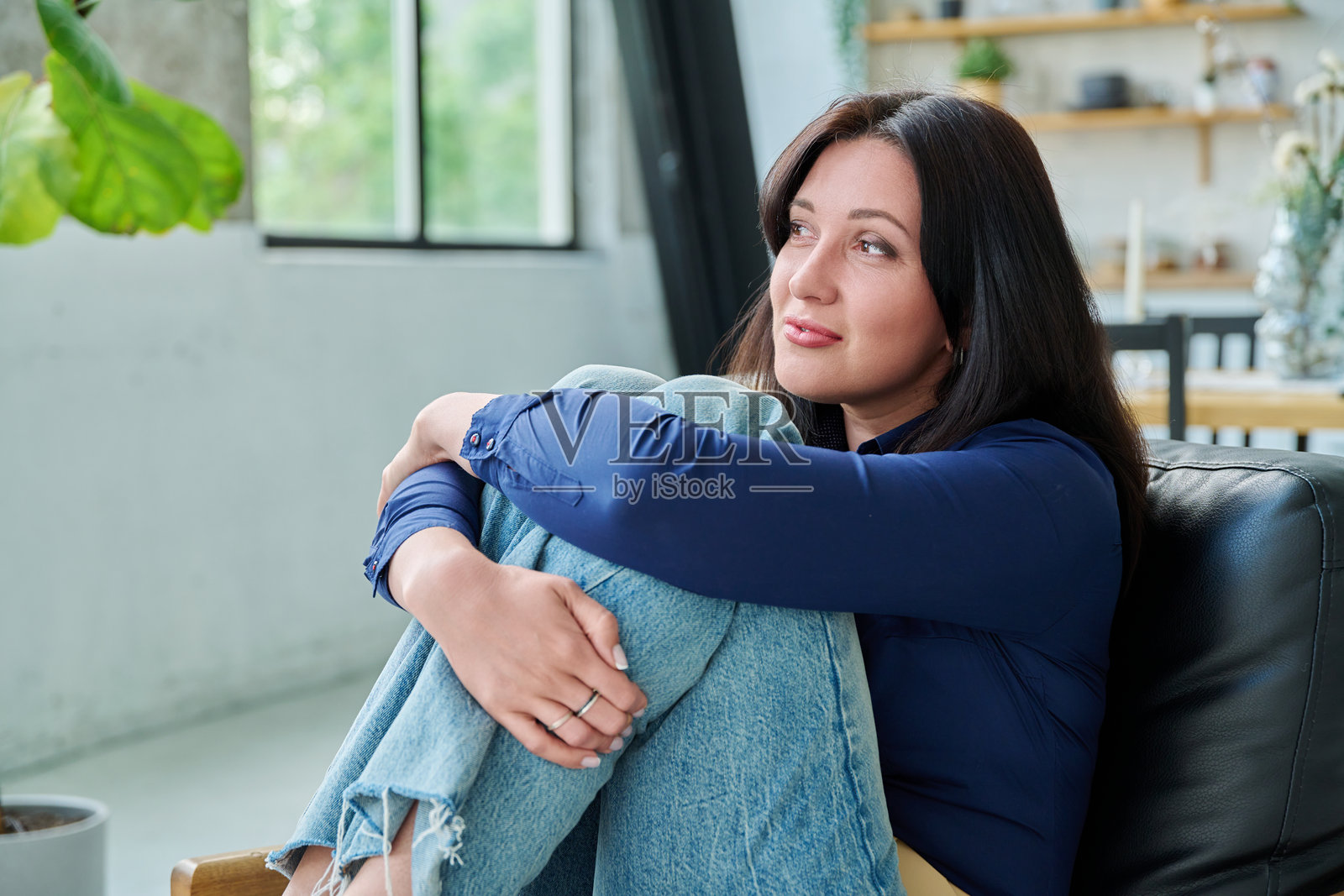 坐在客厅沙发上的美丽三十多岁微笑女性肖像照片摄影图片