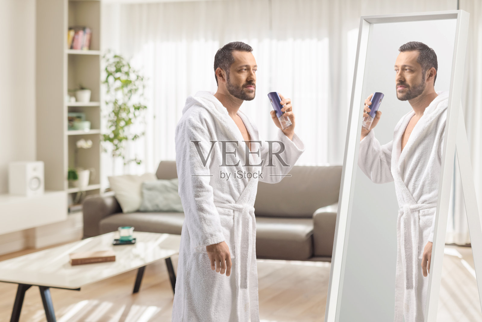 穿着浴袍的男人在镜子前喷香水照片摄影图片