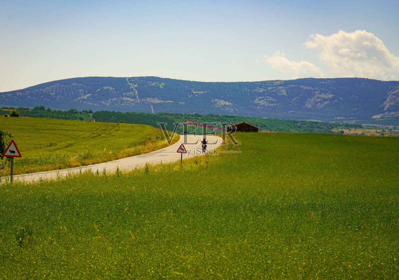 一条穿过草地和山脉的沥青道路照片摄影图片