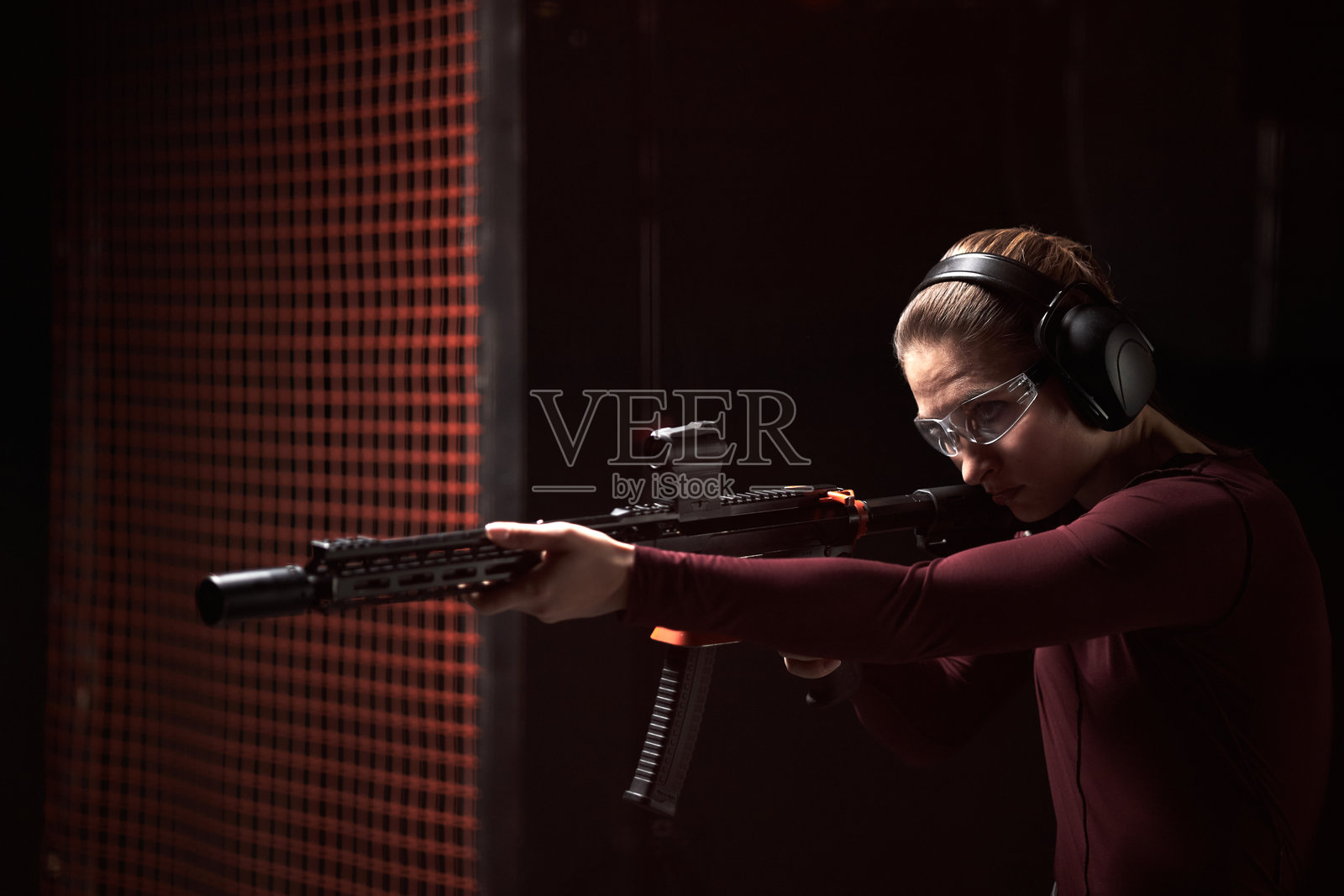 白人年轻女性在室内射击俱乐部练习射击步枪照片摄影图片
