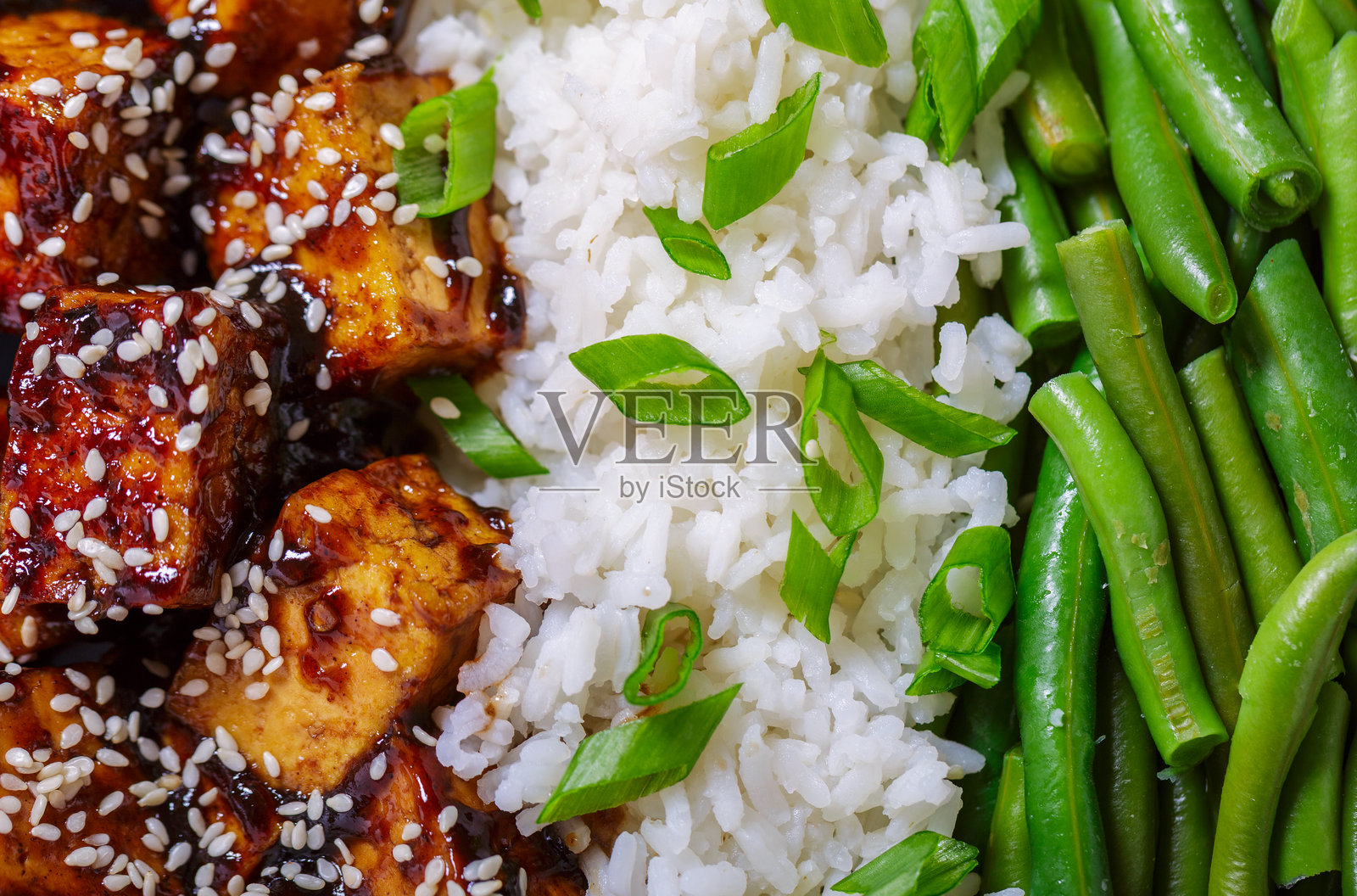 撒有芝麻的炸豆腐，背景是米饭和青豆照片摄影图片