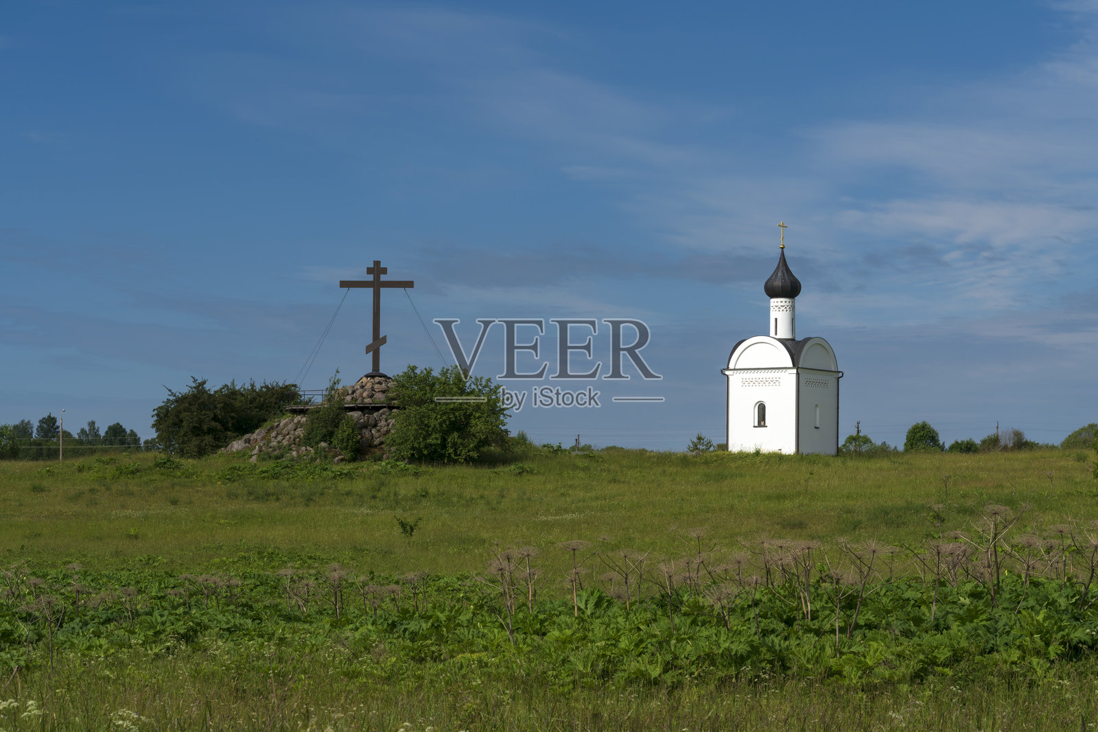 在阳光明媚的夏日，俄罗斯普斯科夫地区佩切尔斯克区的统一俄罗斯圣山上，主权圣母图标教堂和崇拜十字架的景观。照片摄影图片