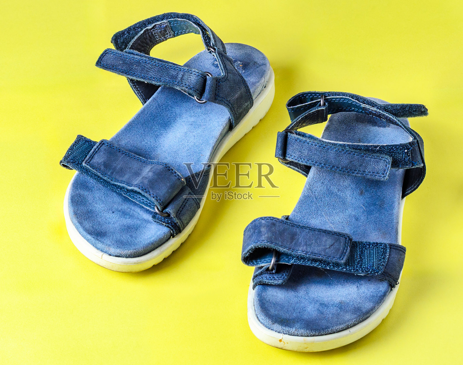 黄色背景上的蓝色女士凉鞋，夏季时尚鞋履俯视图照片摄影图片