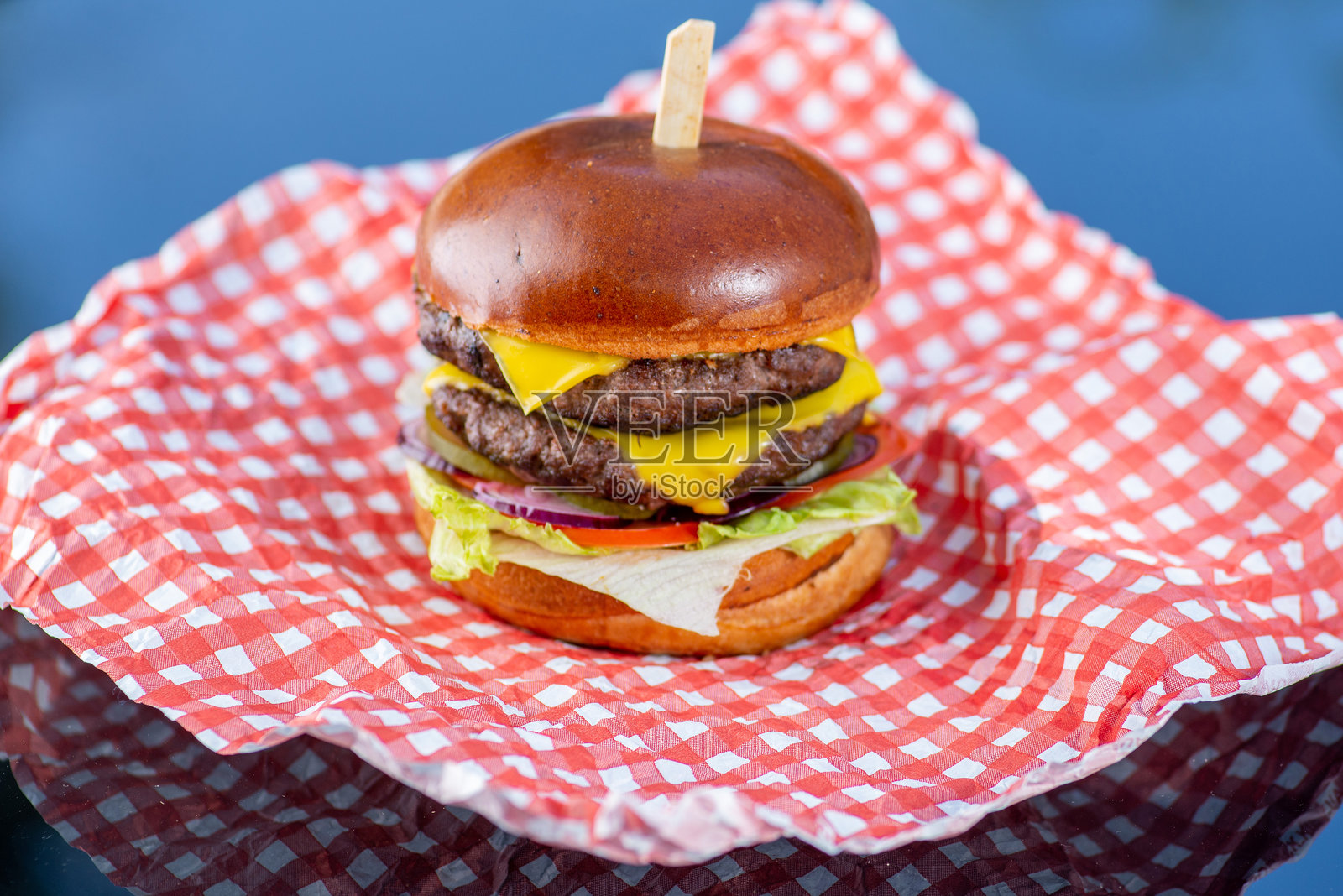 双肉饼汉堡配蔬菜，放在纸上照片摄影图片