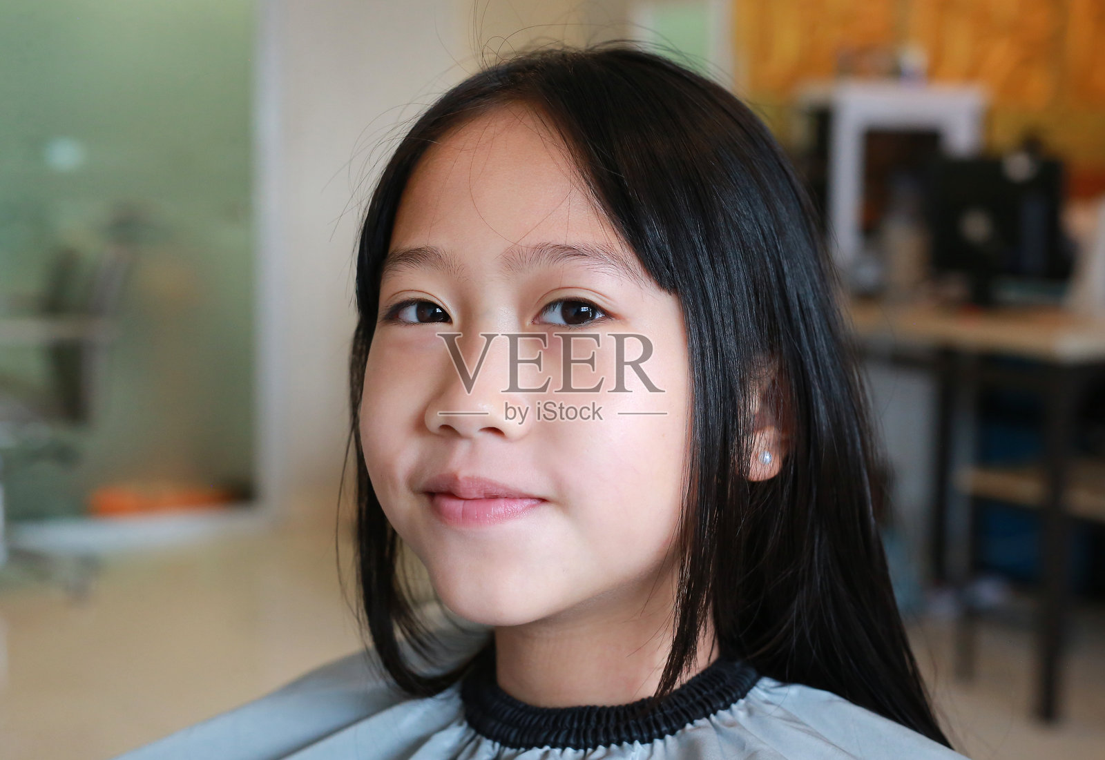 亚洲女孩在美容院理发的肖像特写。照片摄影图片